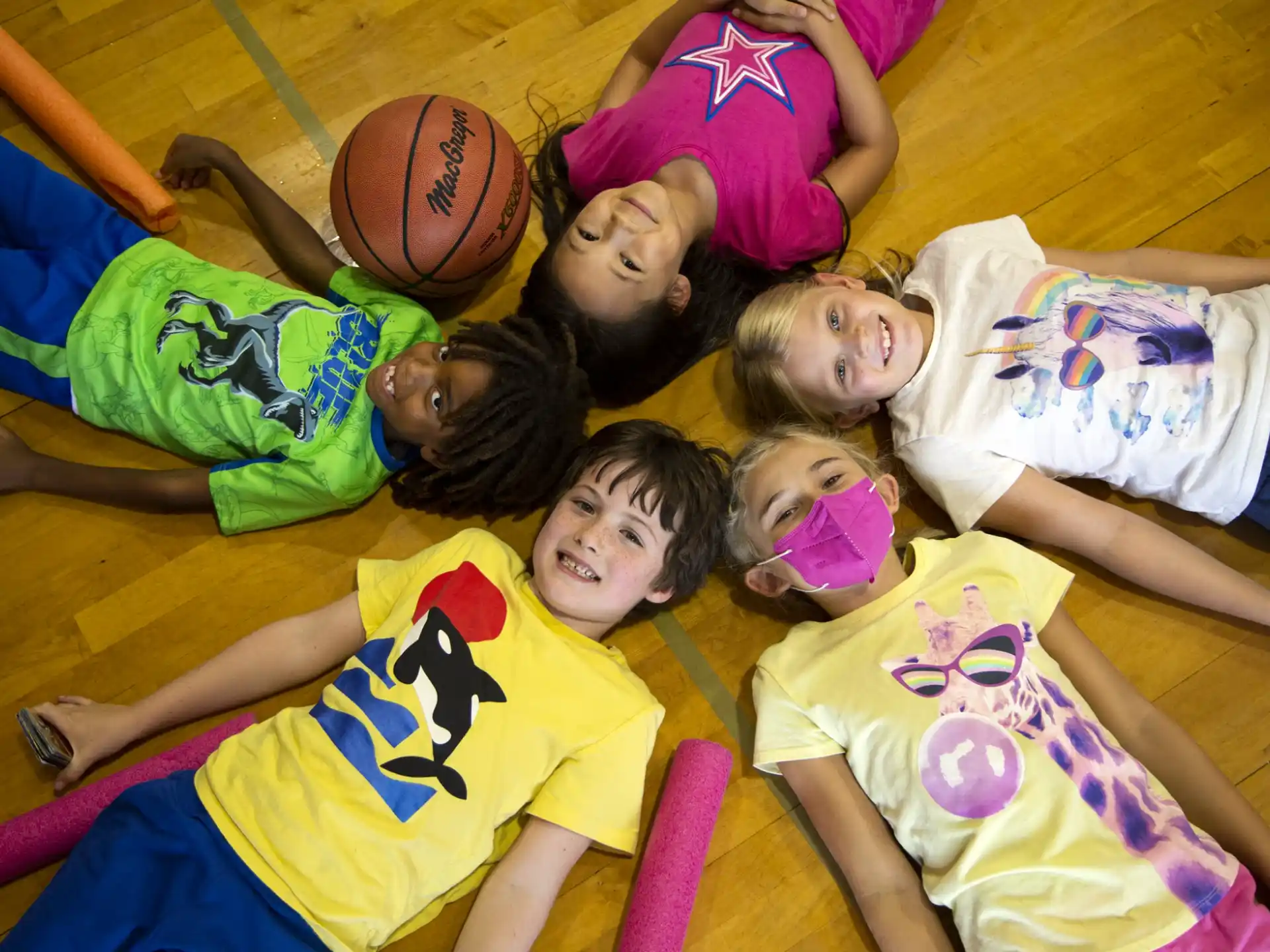 a group of kids lying on the floor with a basketball