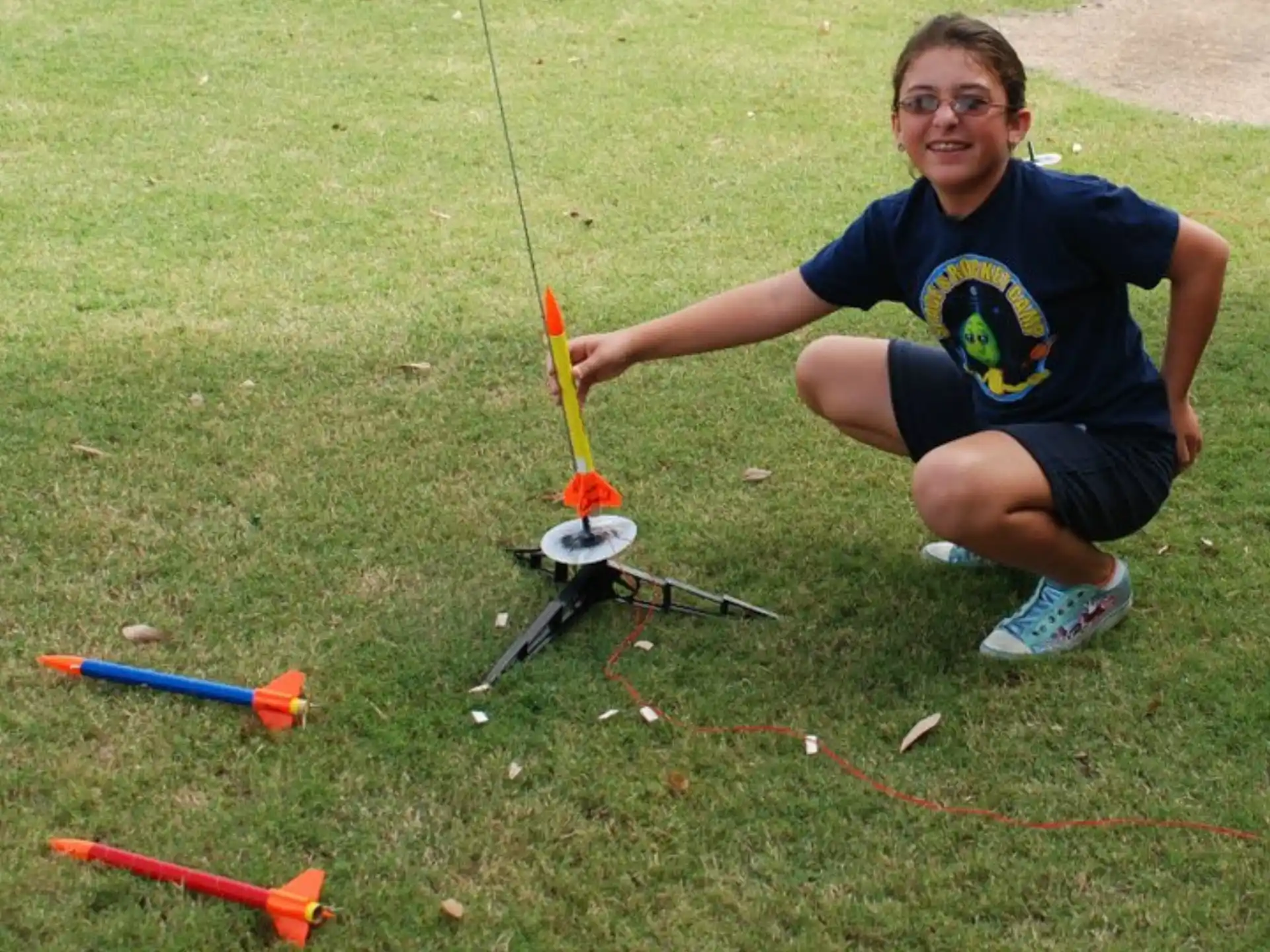 a boy kneeling on grass with a toy gun and a stick