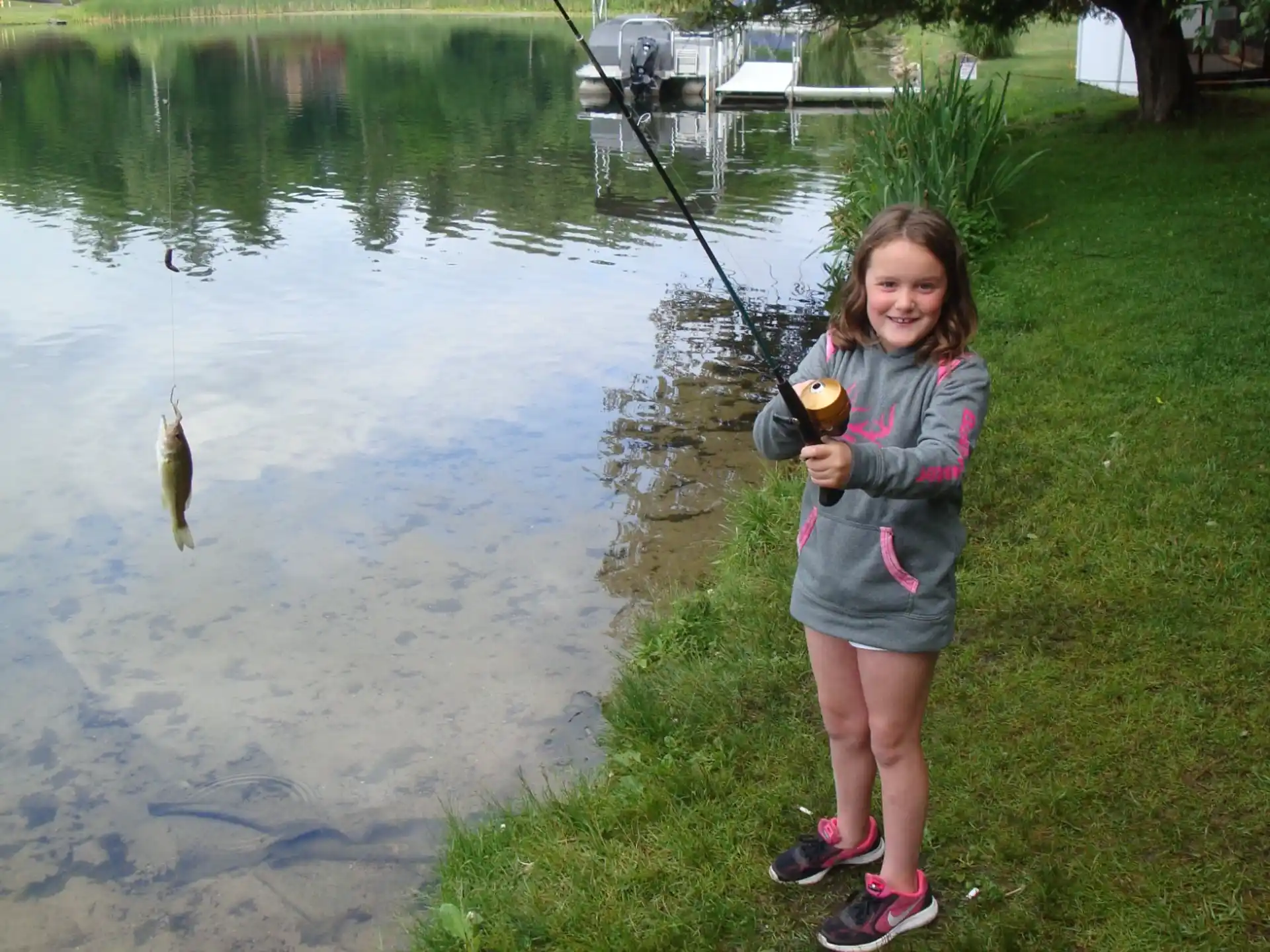 a girl holding a fish and standing next to a body of water