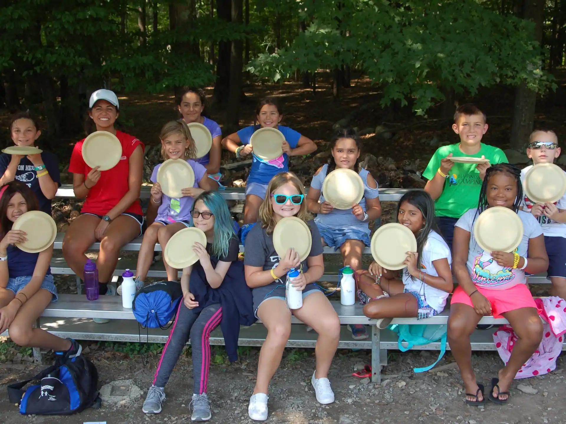 a group of people sitting on a bench holding frisbees