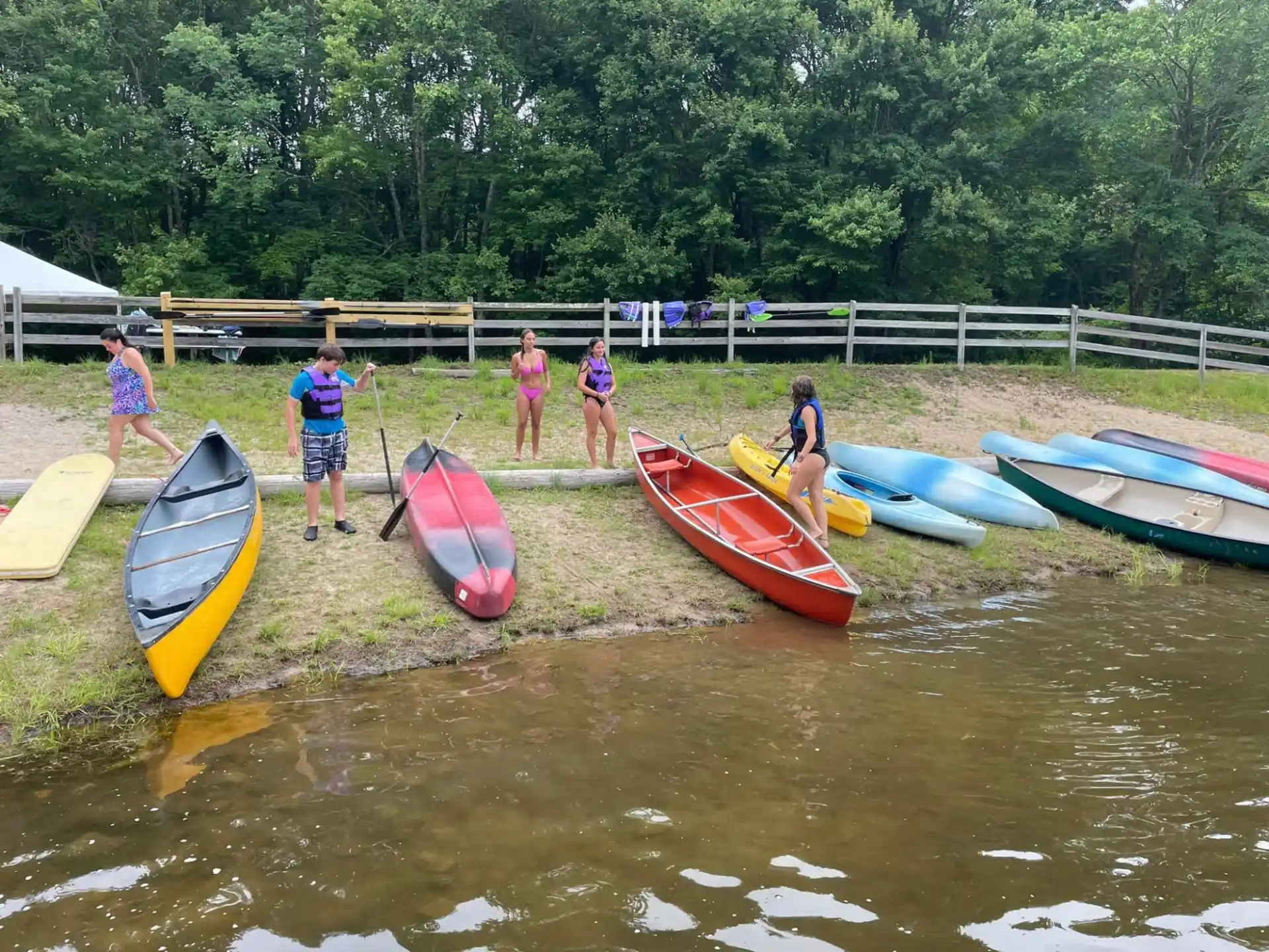 a group of people standing next to kayaks on a river