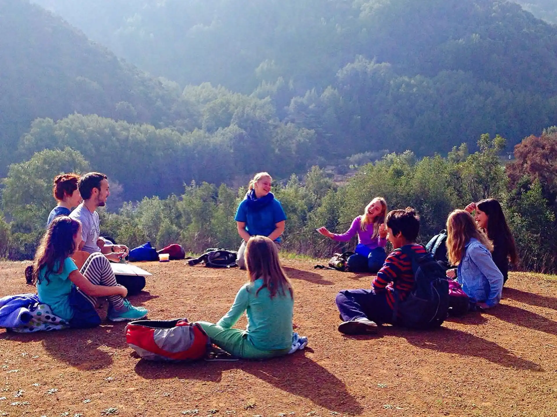 a group of people sitting on a hill overlooking a valley
