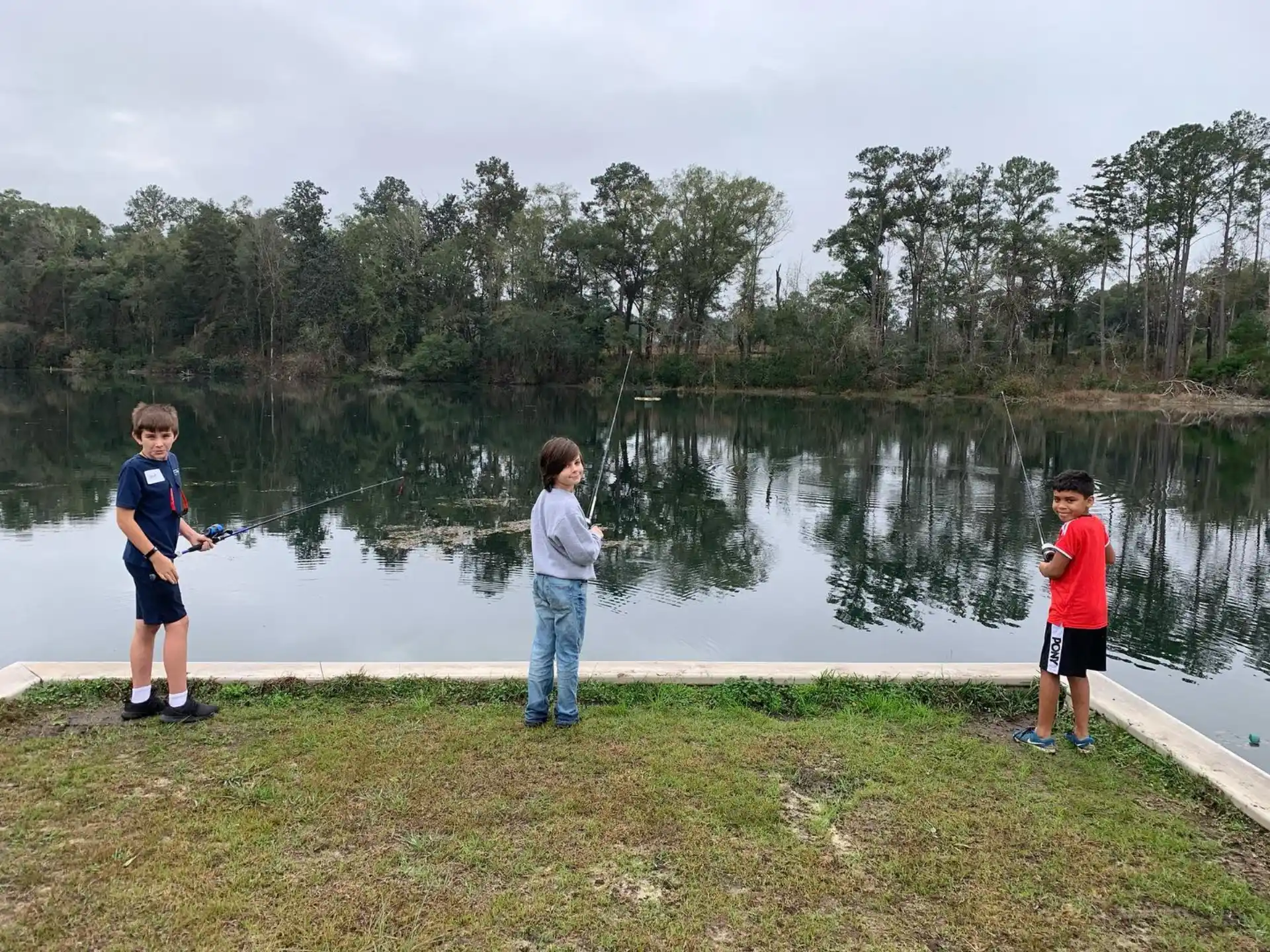 a group of boys standing by a pond