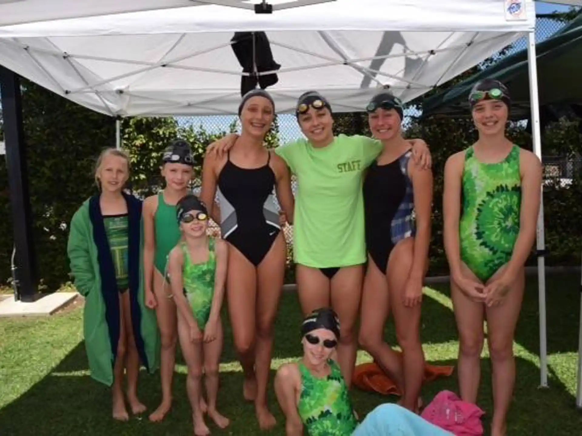 a group of women in swimsuits standing under a tent