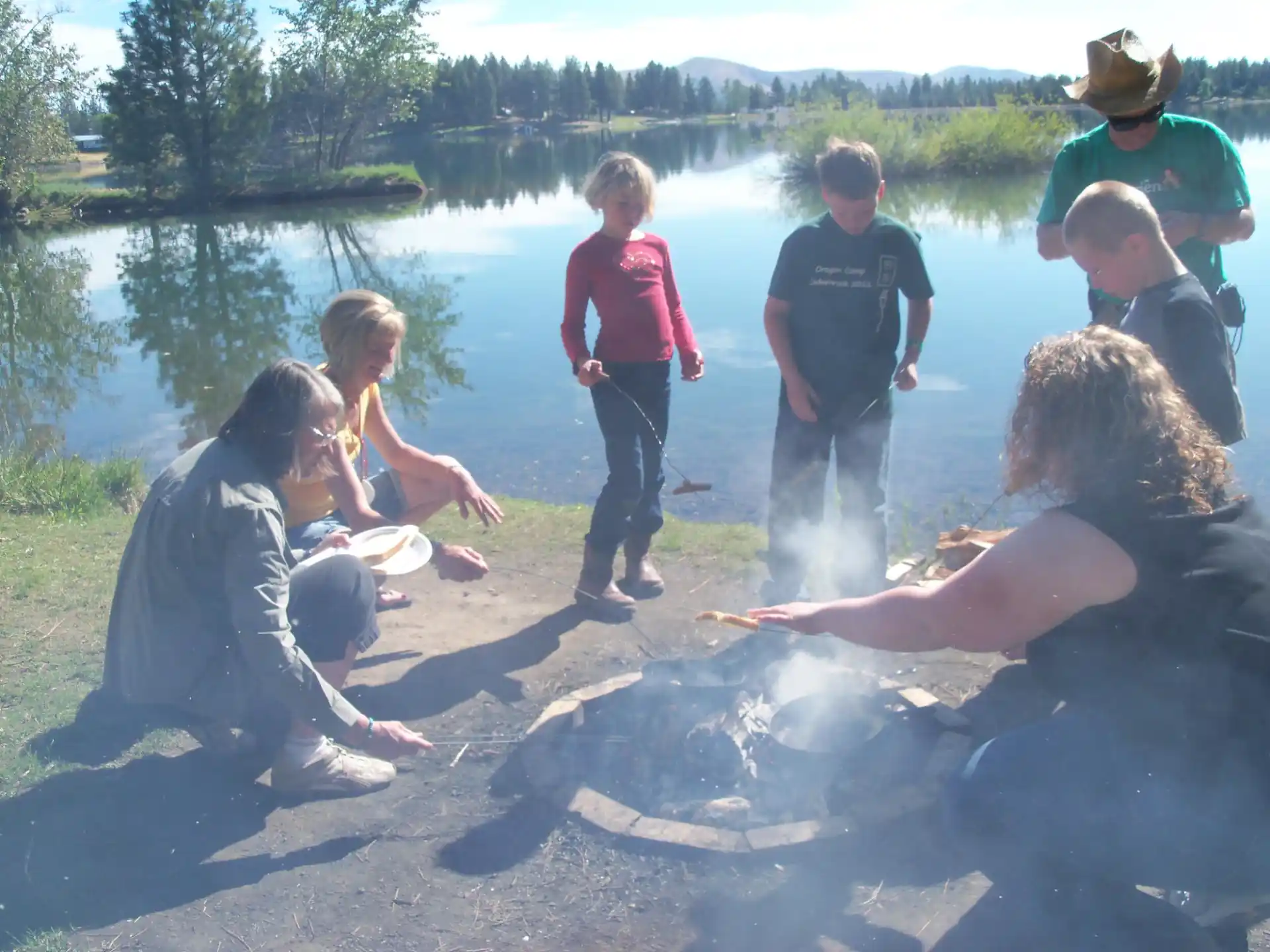 a group of people playing in the sand by a lake