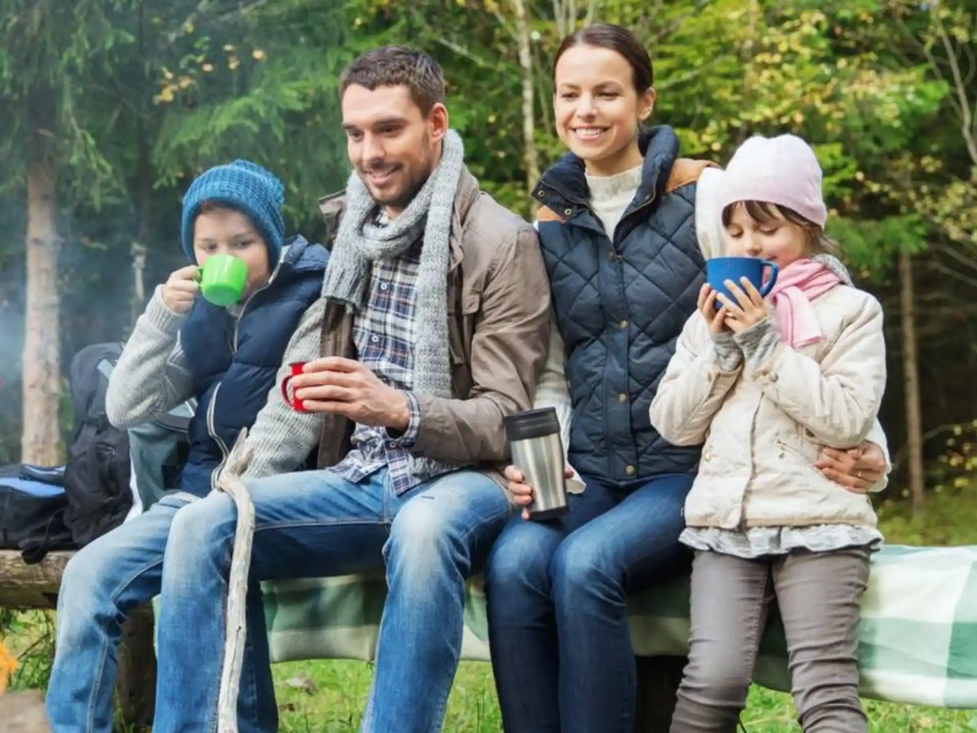 a group of people sitting on a bench with drinks
