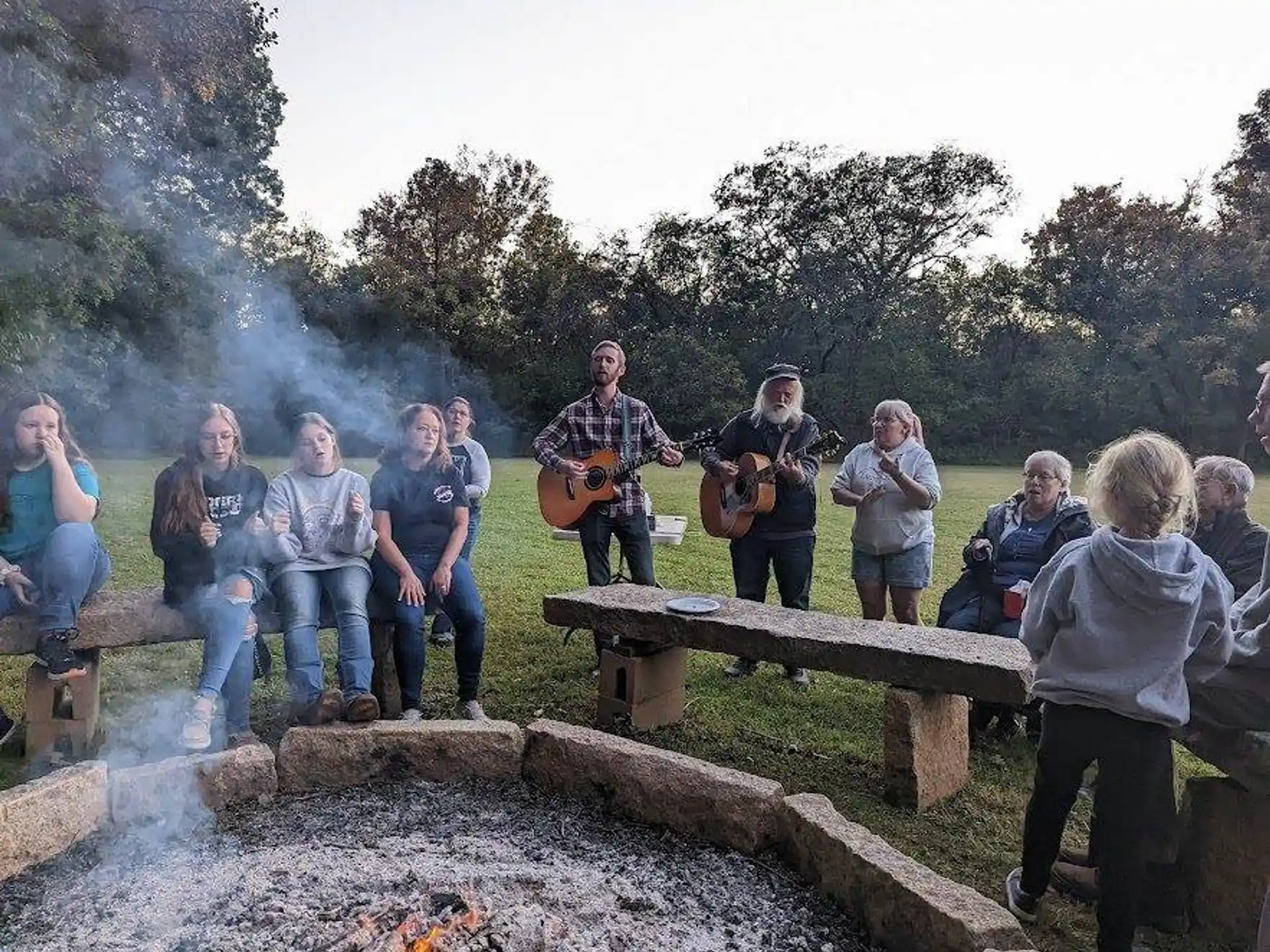a group of people sitting on a bench with a person playing guitar