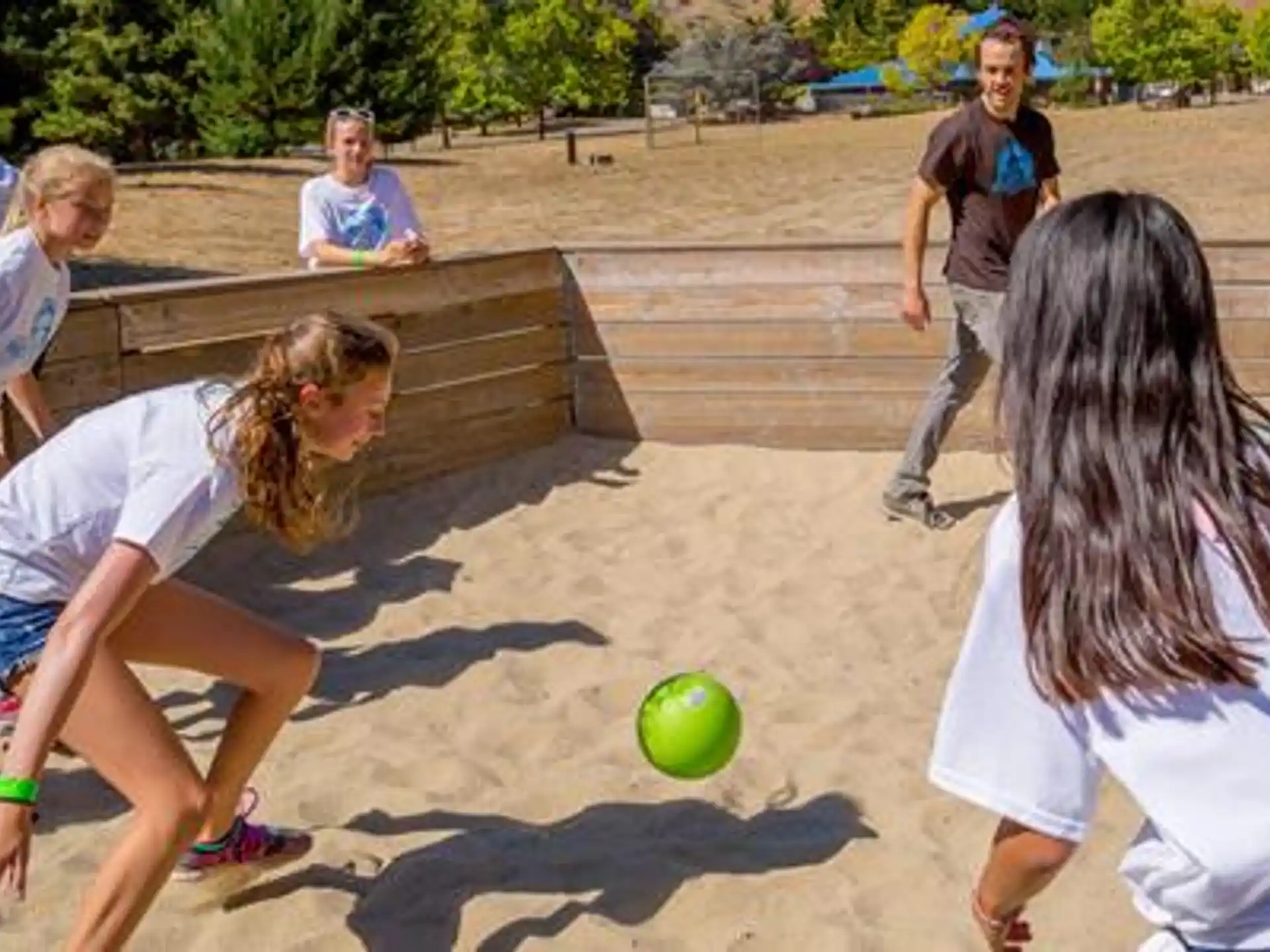 a group of people playing with a ball on a sandy beach