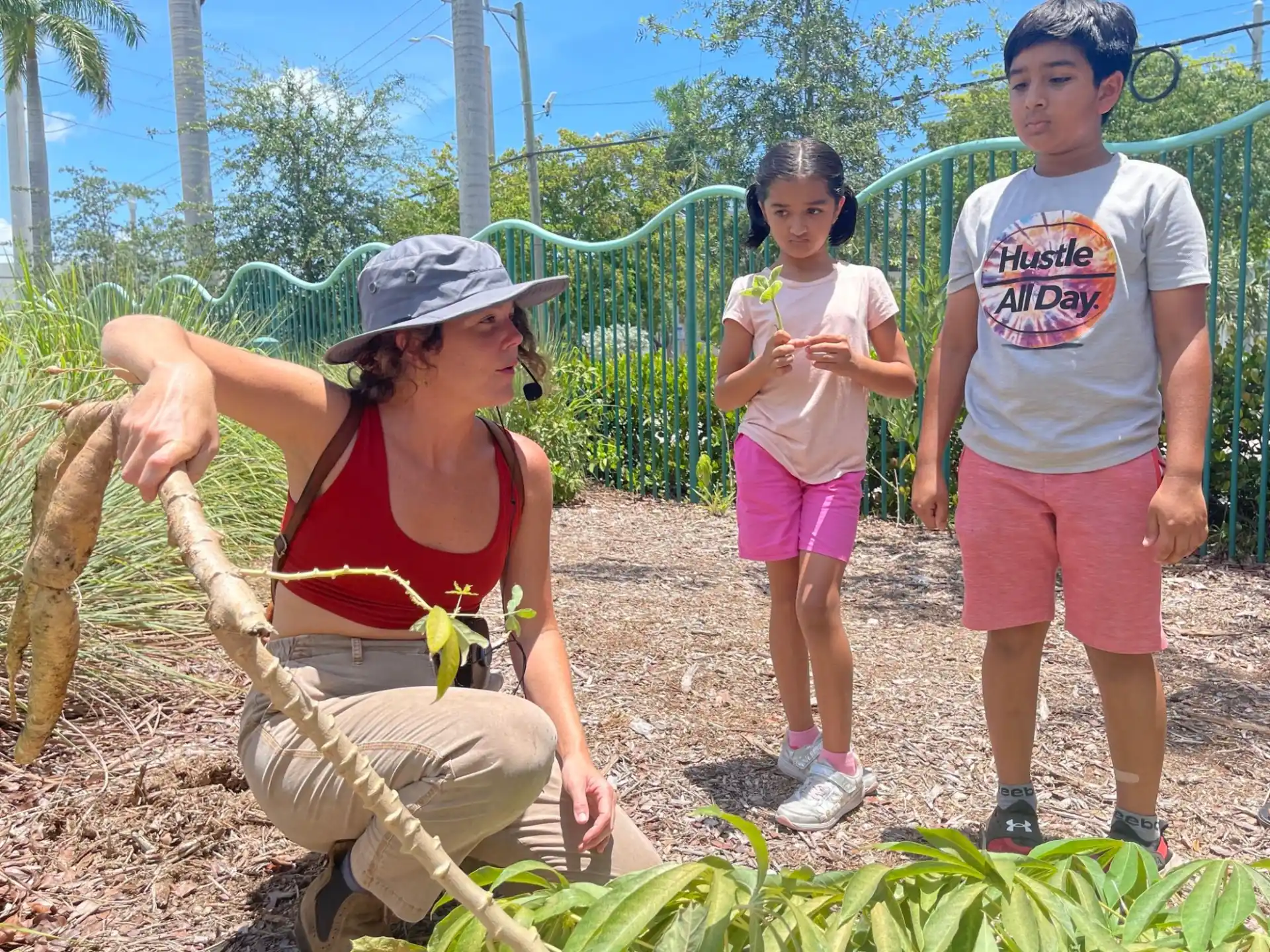 a group of children standing next to a person holding a large green vegetable