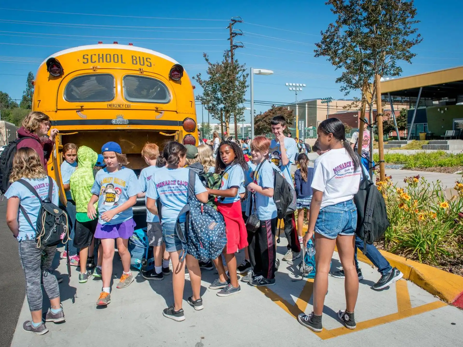 a group of people standing in front of a yellow bus