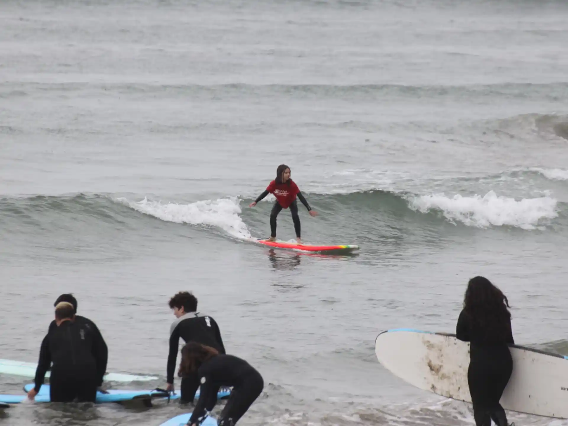 a group of surfers stand on a small wave