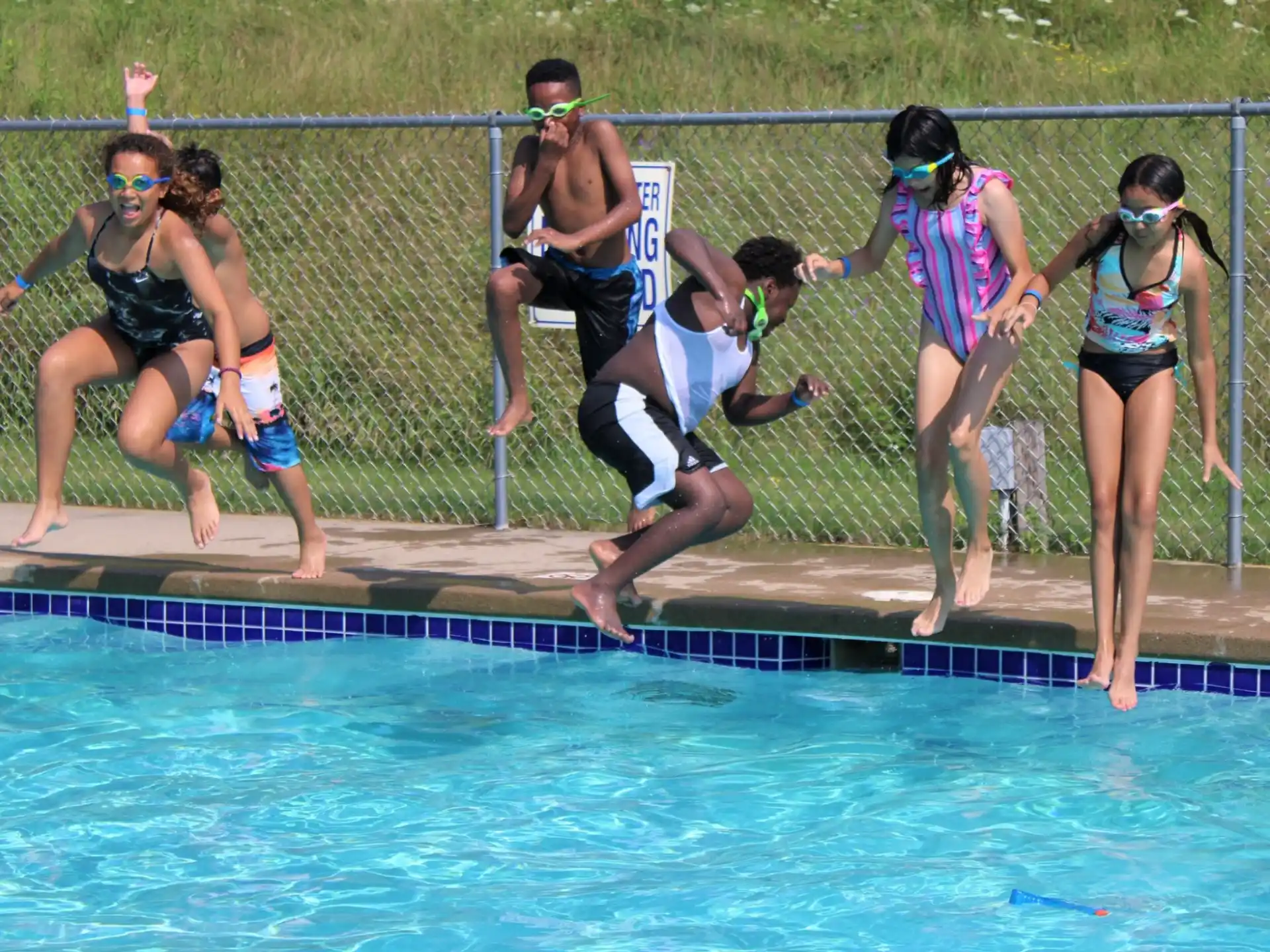 a group of people jumping into a pool