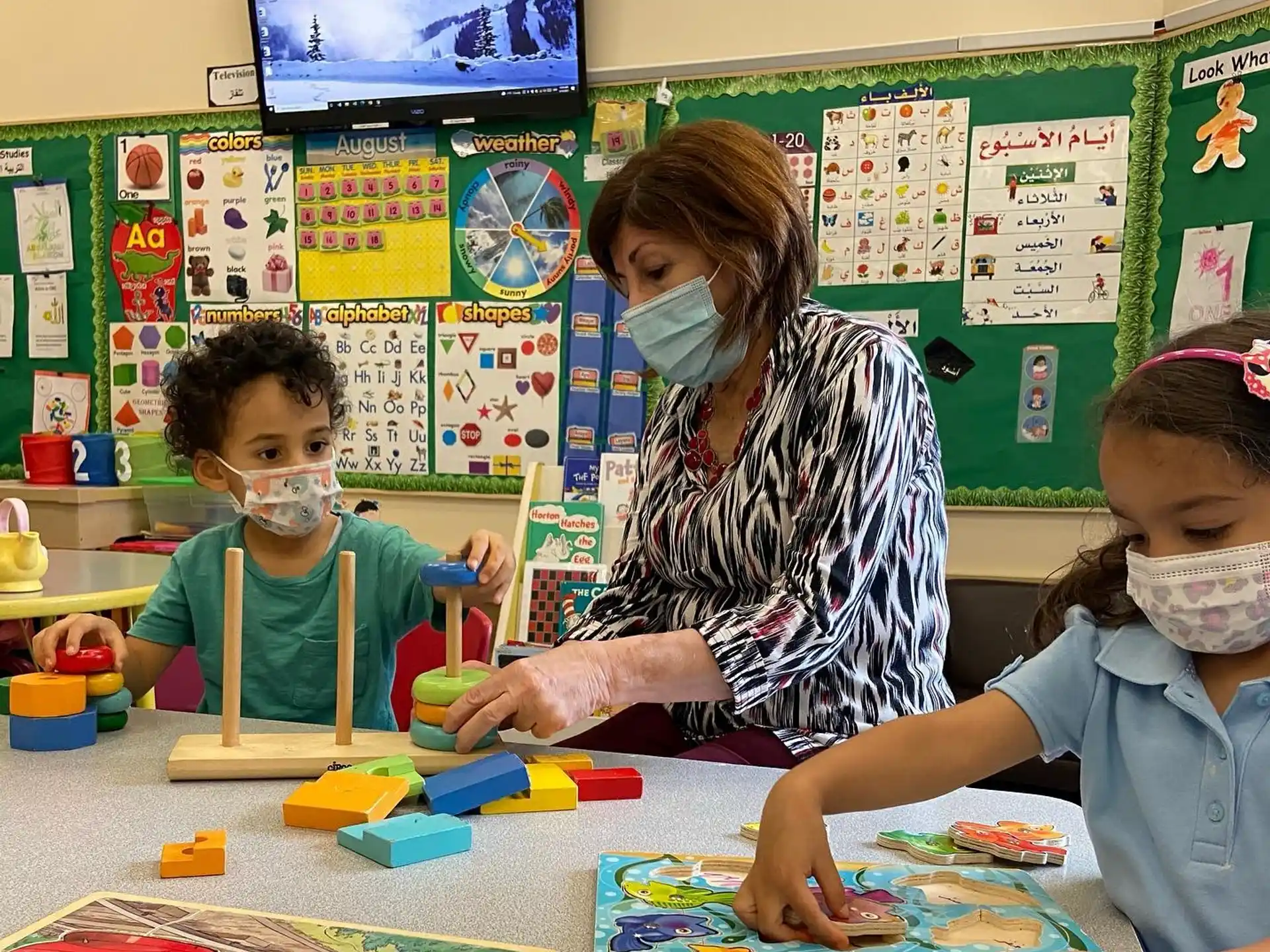 a person and several children playing with toys in a classroom