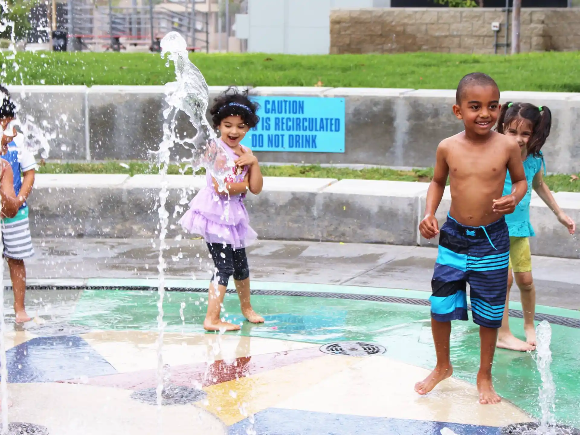 a group of children playing in a water fountain