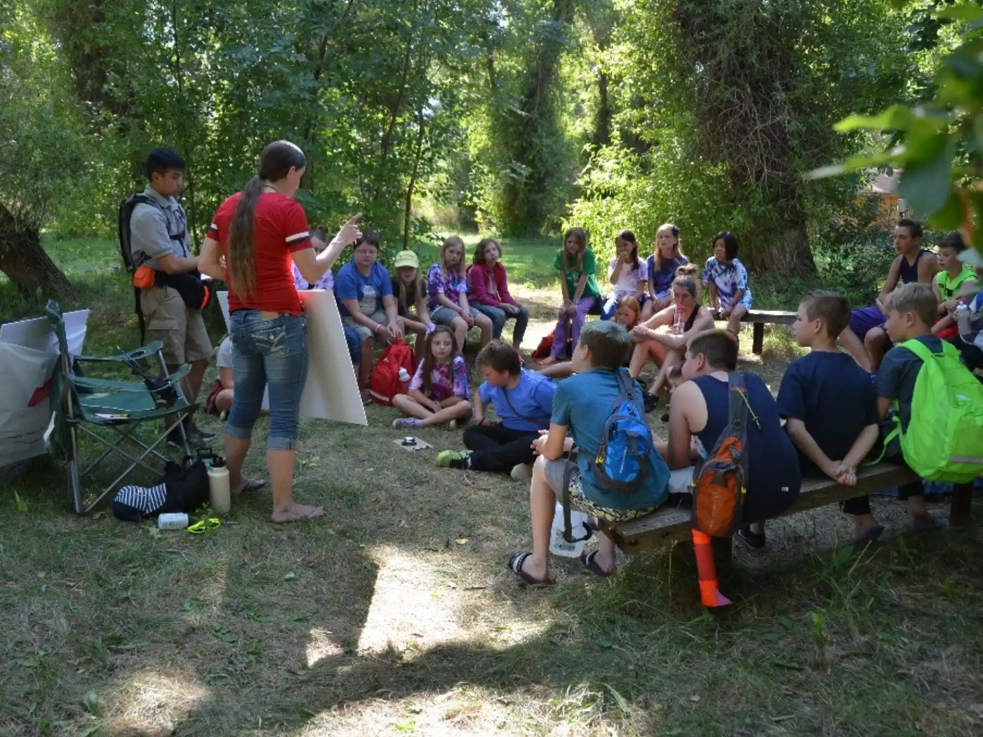a group of people sitting on the ground in a forest