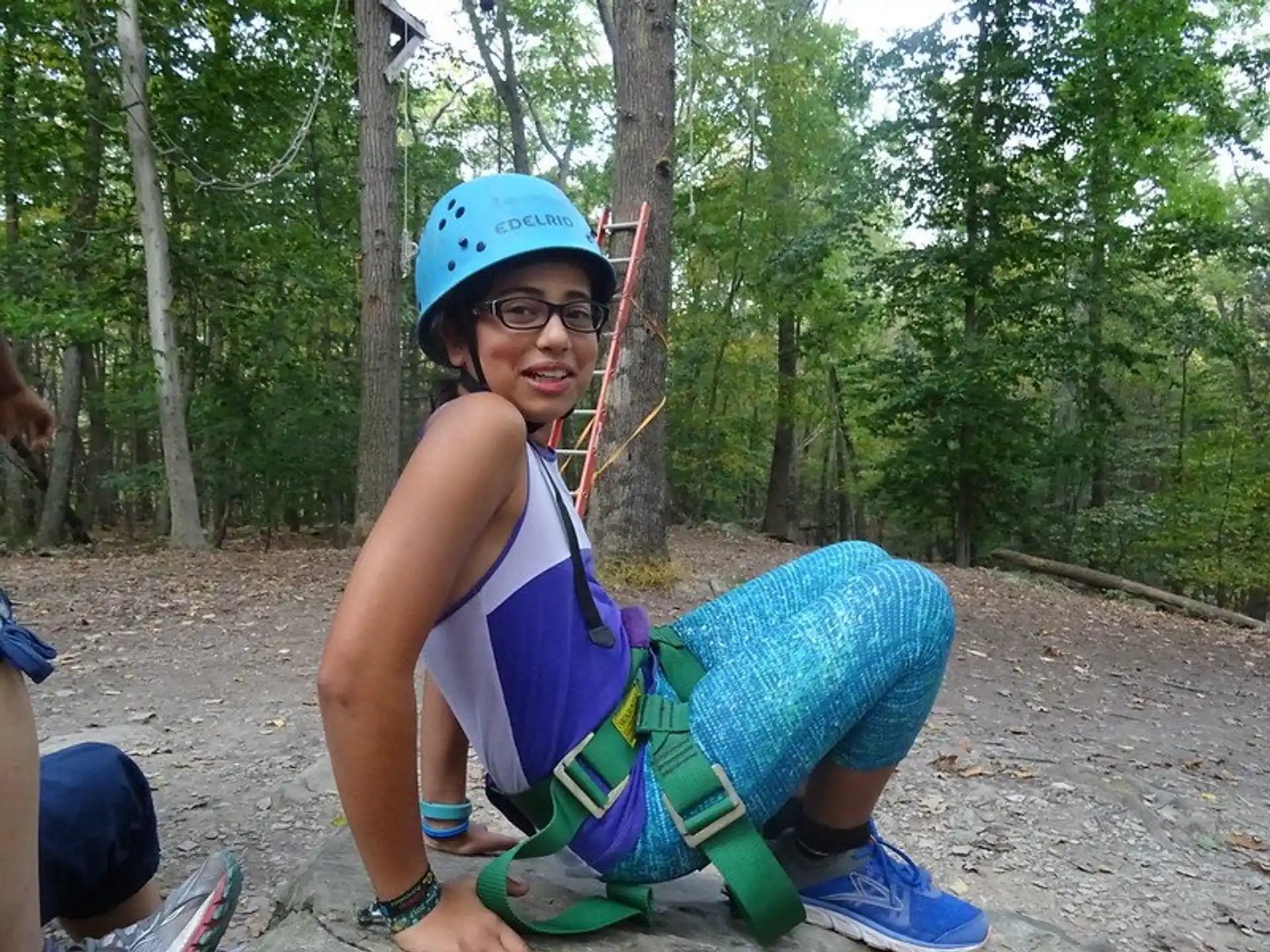 a person wearing a helmet and sitting on a swing in the woods