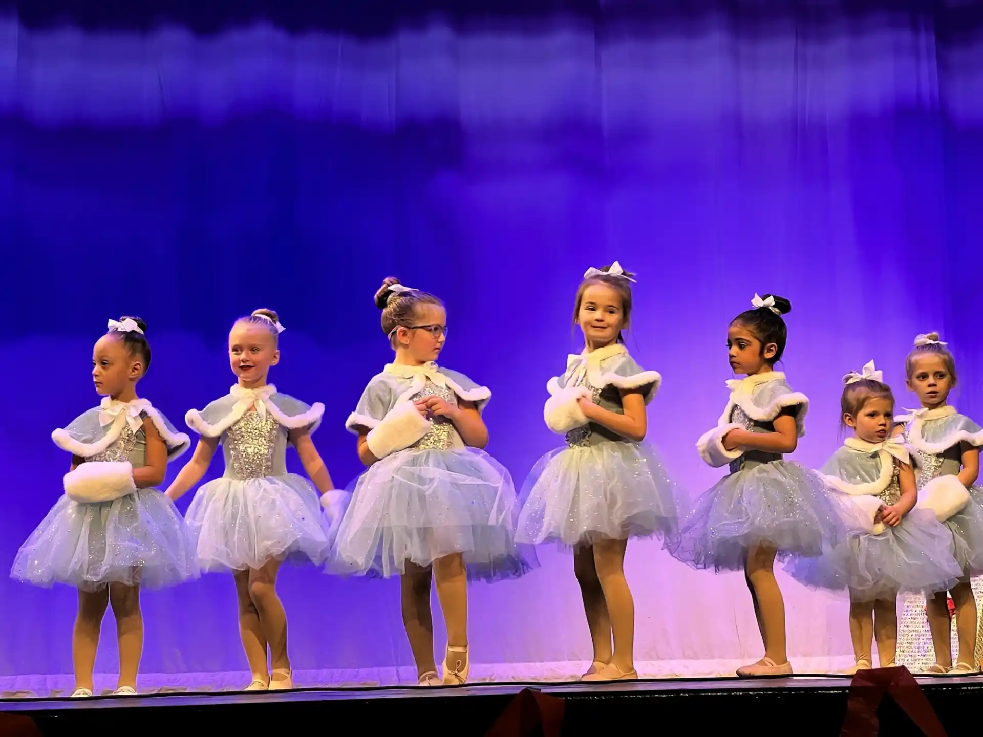 a group of girls in dresses on a stage