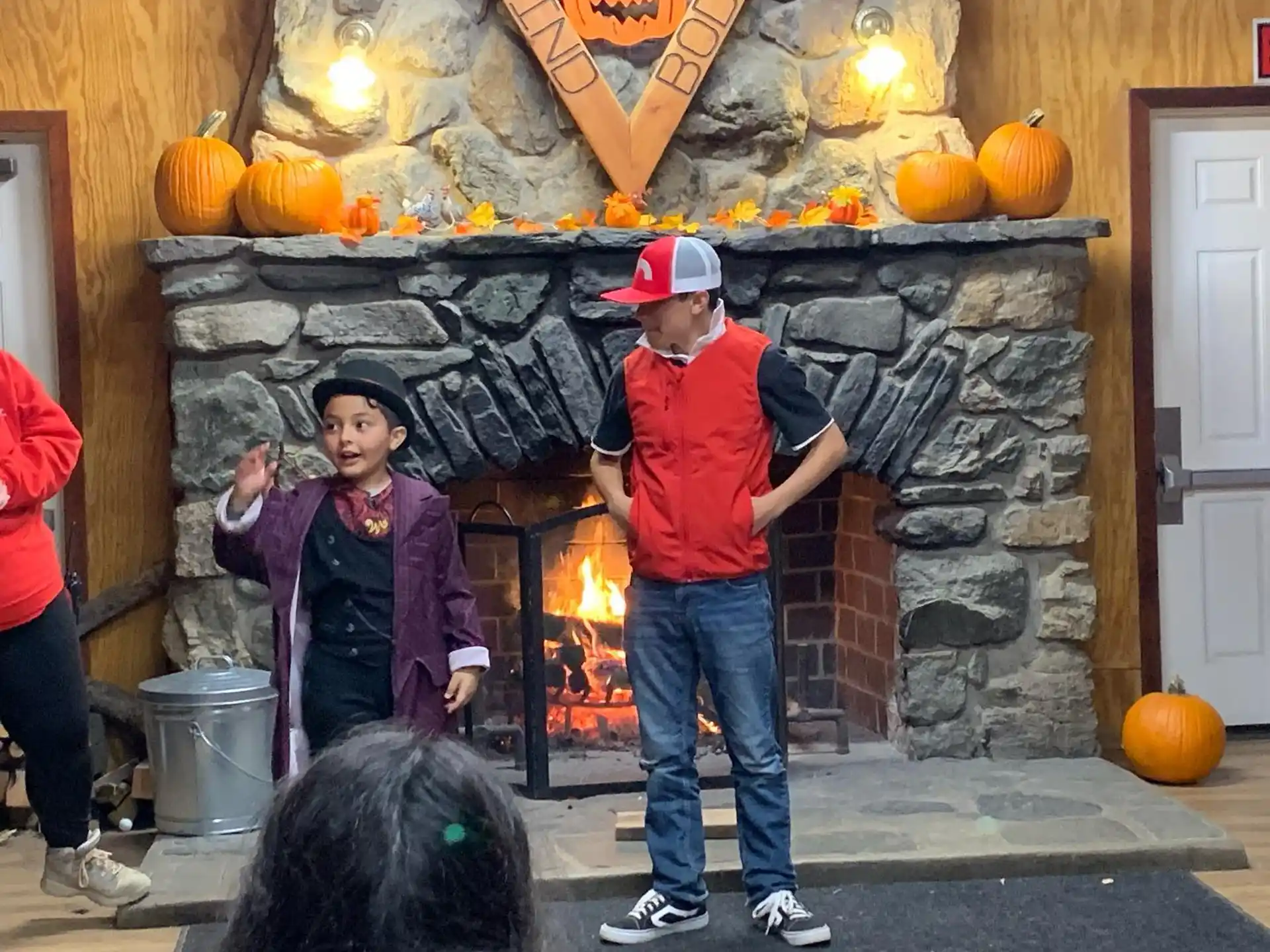 a man and a woman standing in front of a fireplace with pumpkins