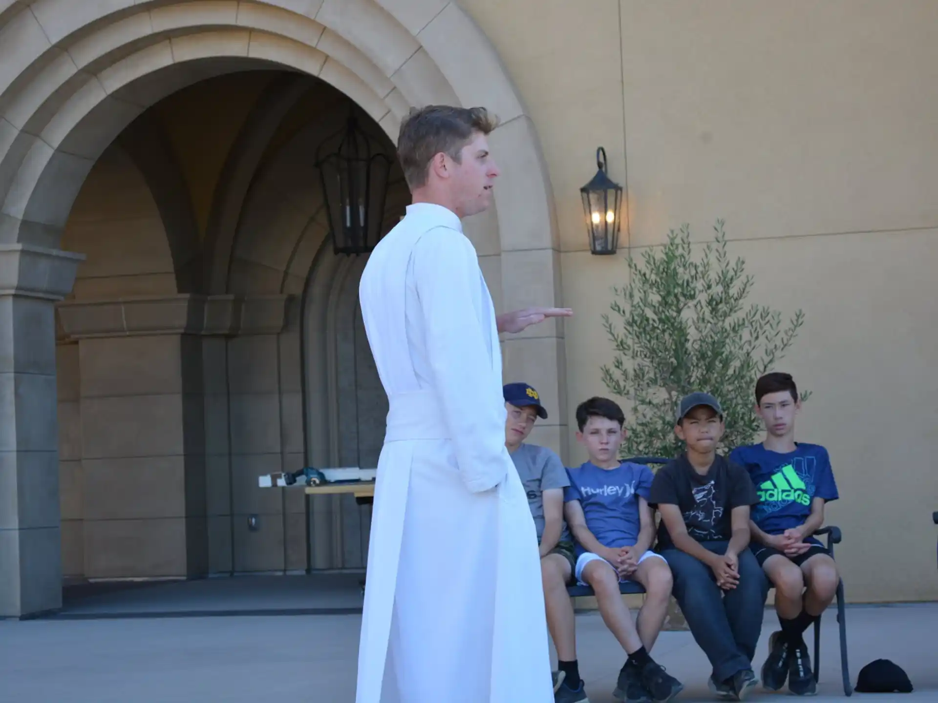 a person in a white robe standing in front of a group of people