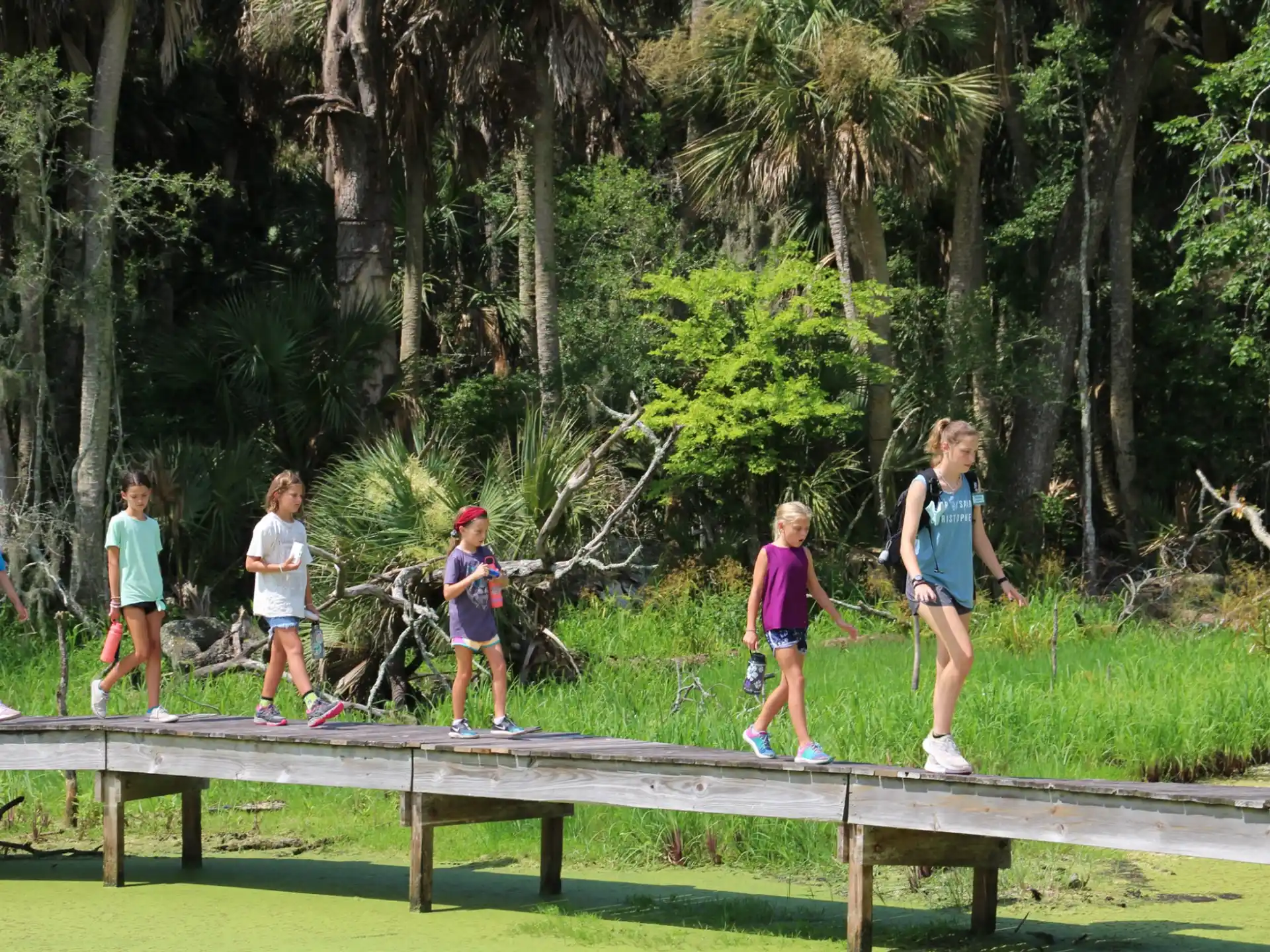 a group of people running on a wooden bridge in a park