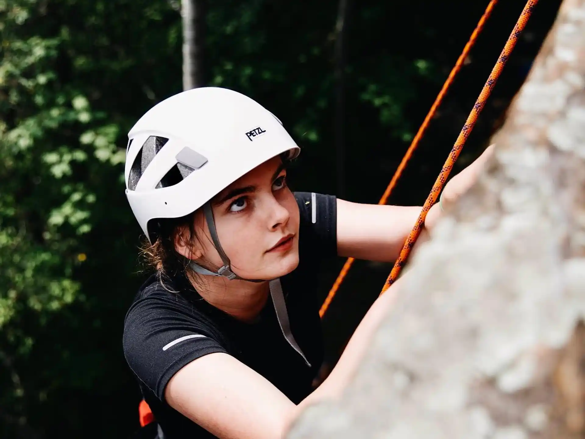 a person wearing a helmet and climbing a rock wall
