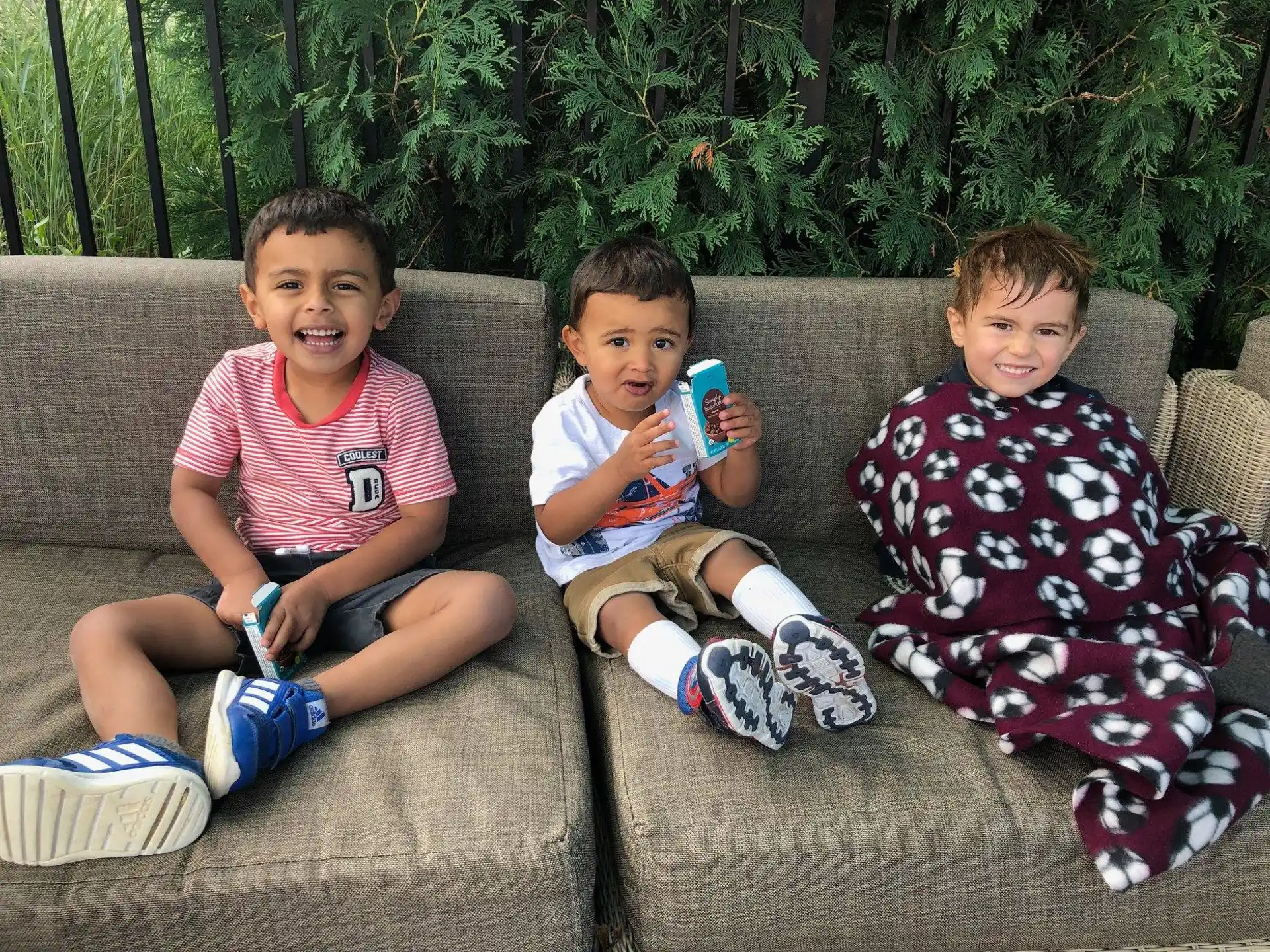 a group of boys sitting on a couch and holding cell phones