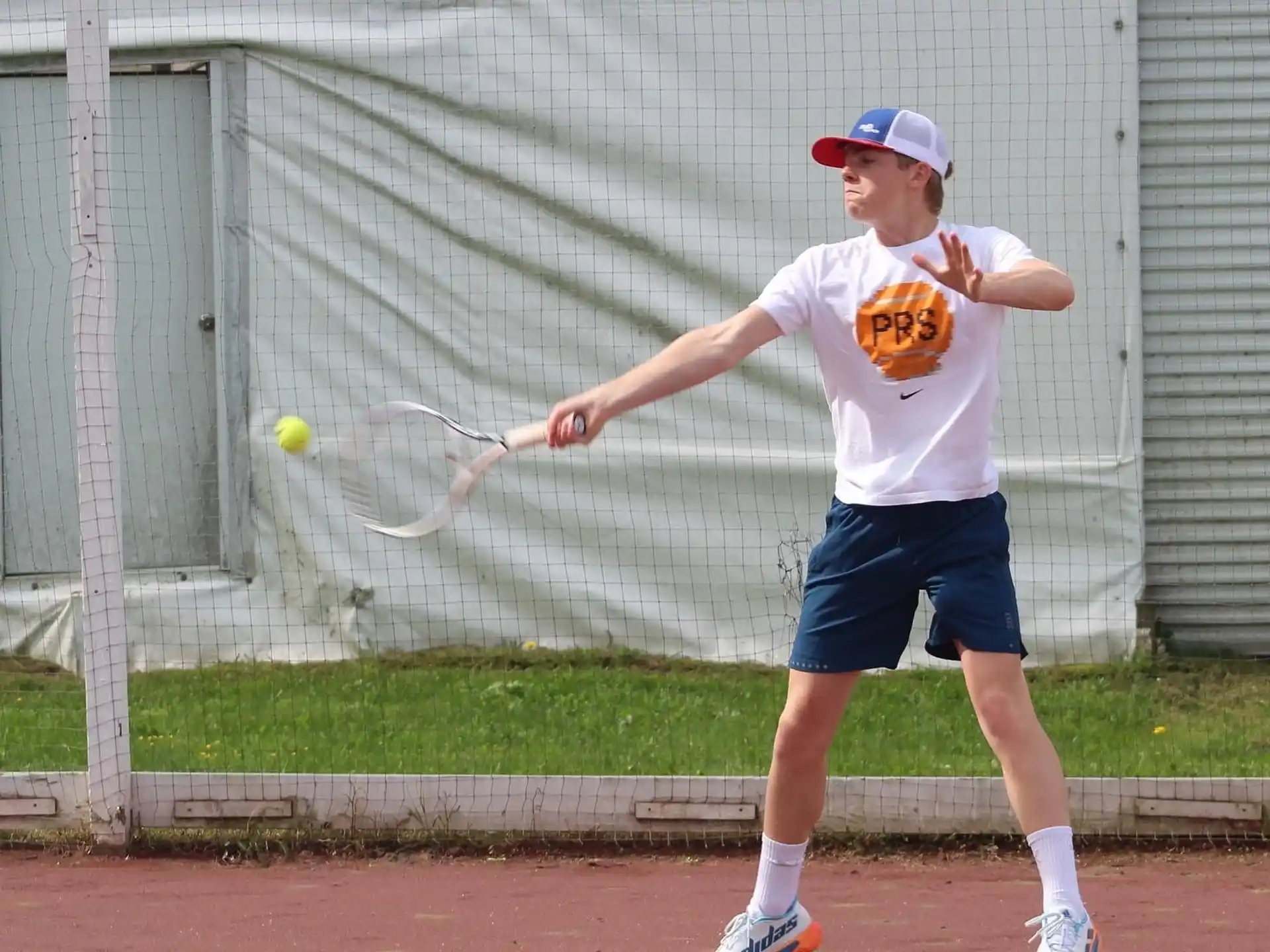 a boy hitting a ball with a tennis racket