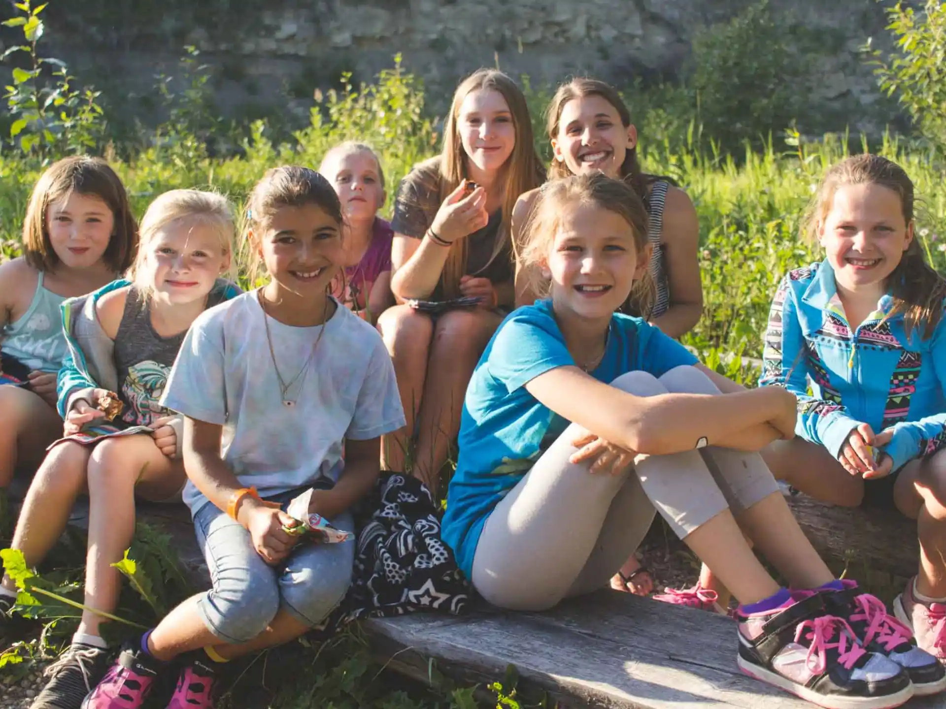 a group of girls sitting on a log posing for a photo