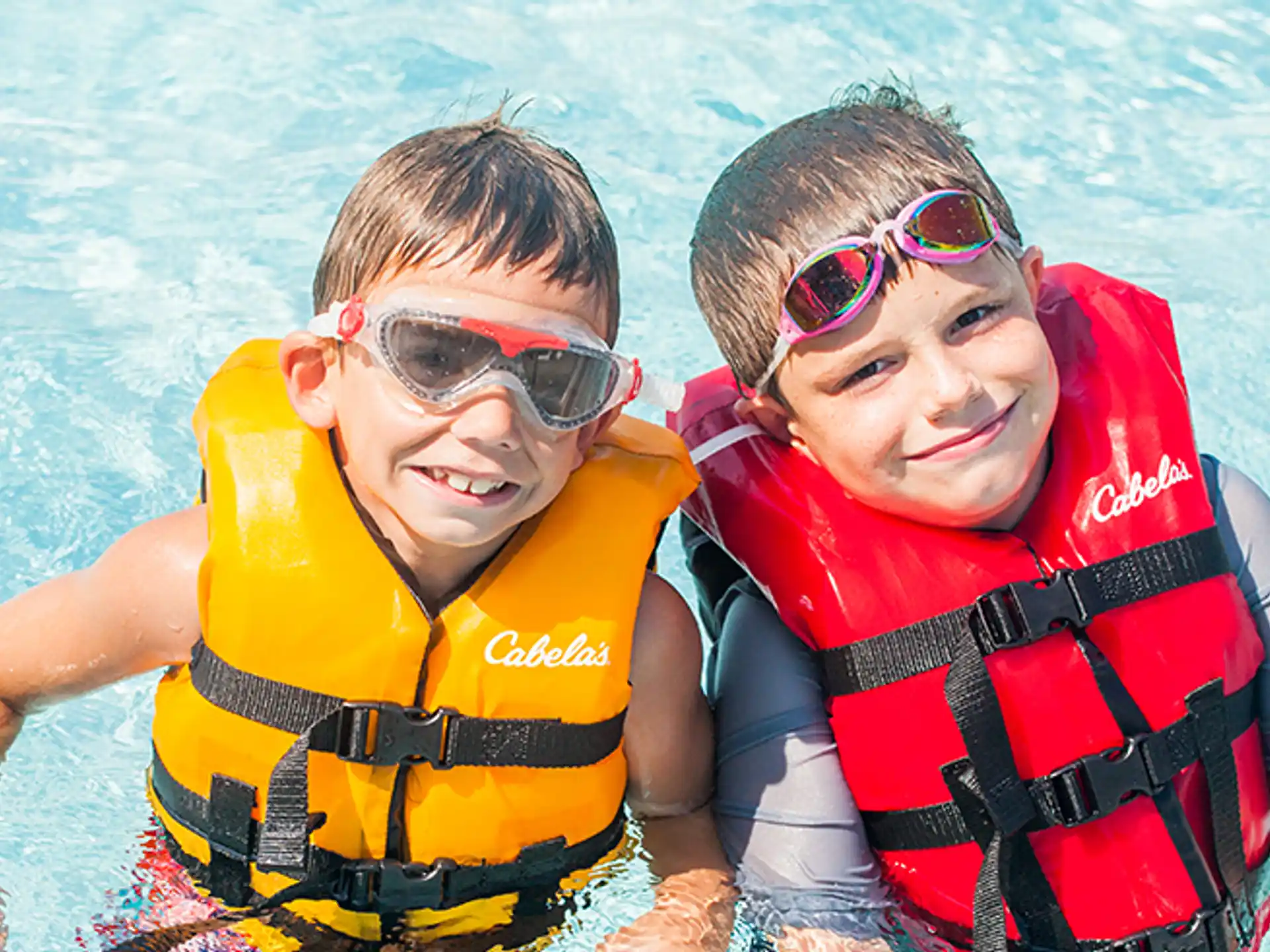 a couple of kids in life jackets in a pool