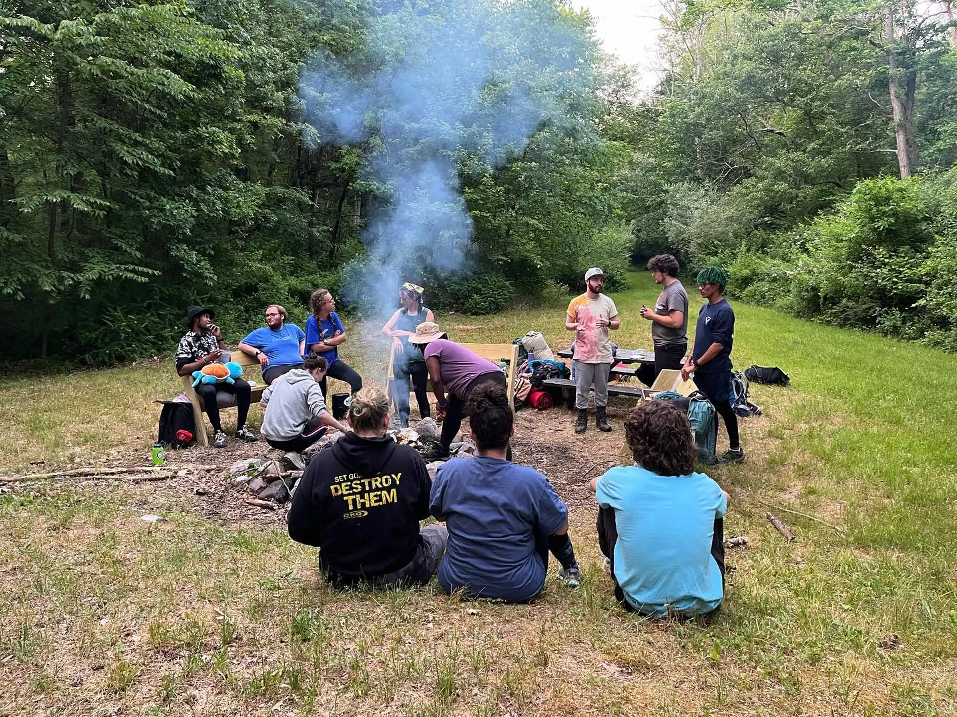 a group of people sitting on a picnic table in a forest