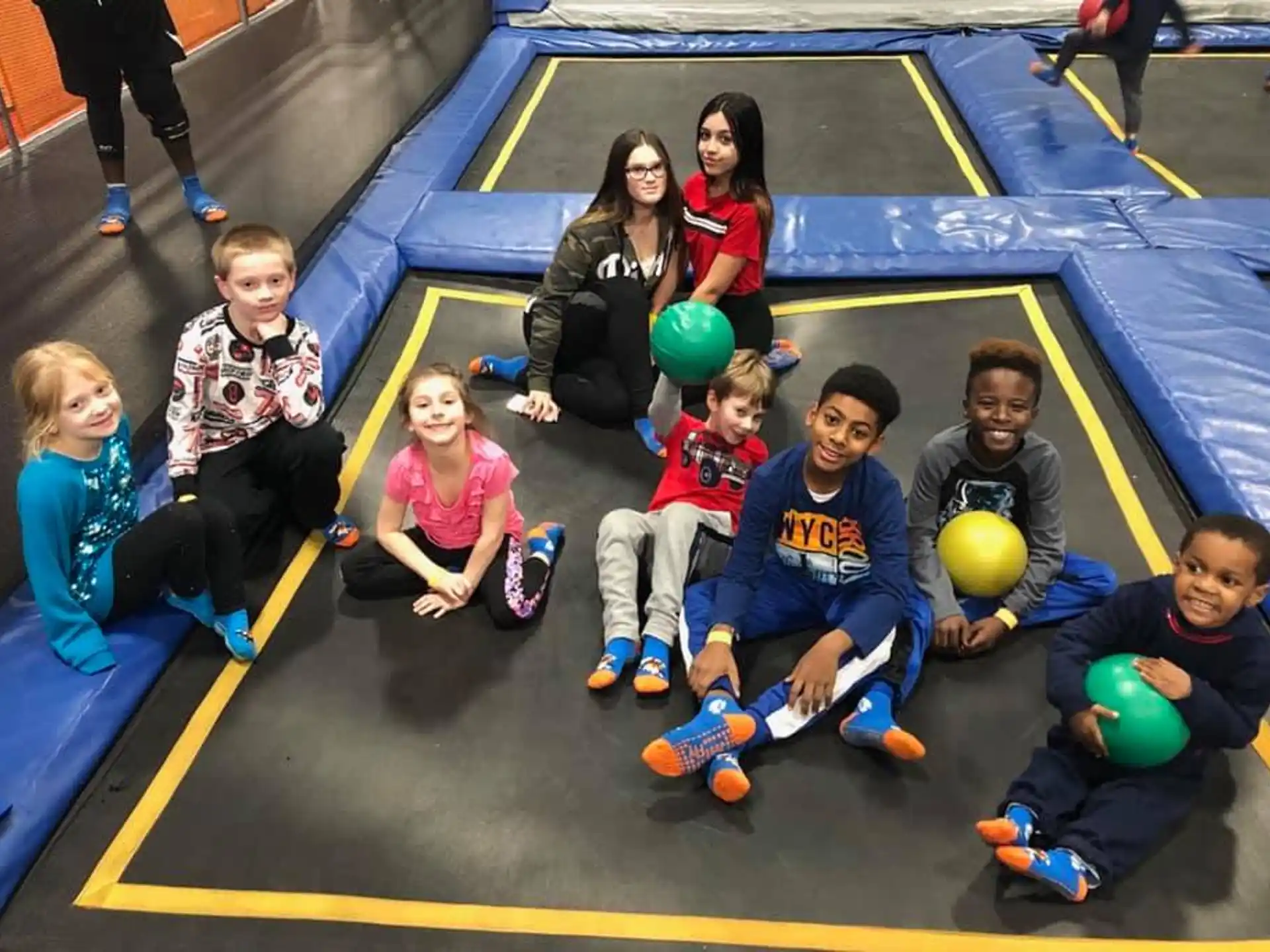 a group of kids sitting on the floor with balls
