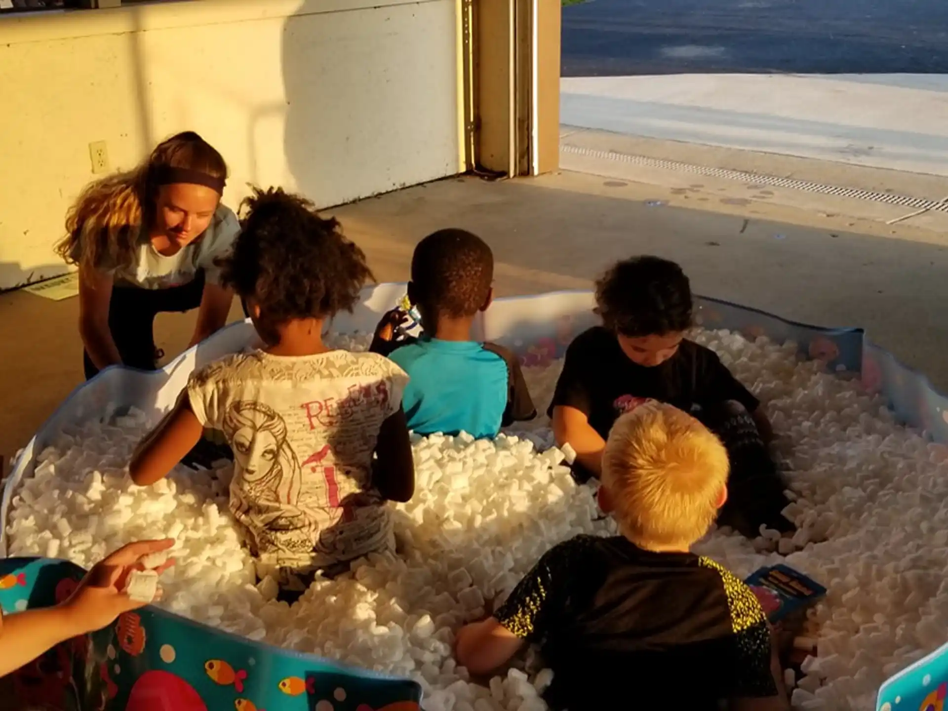 a group of children sitting on a blanket on a beach