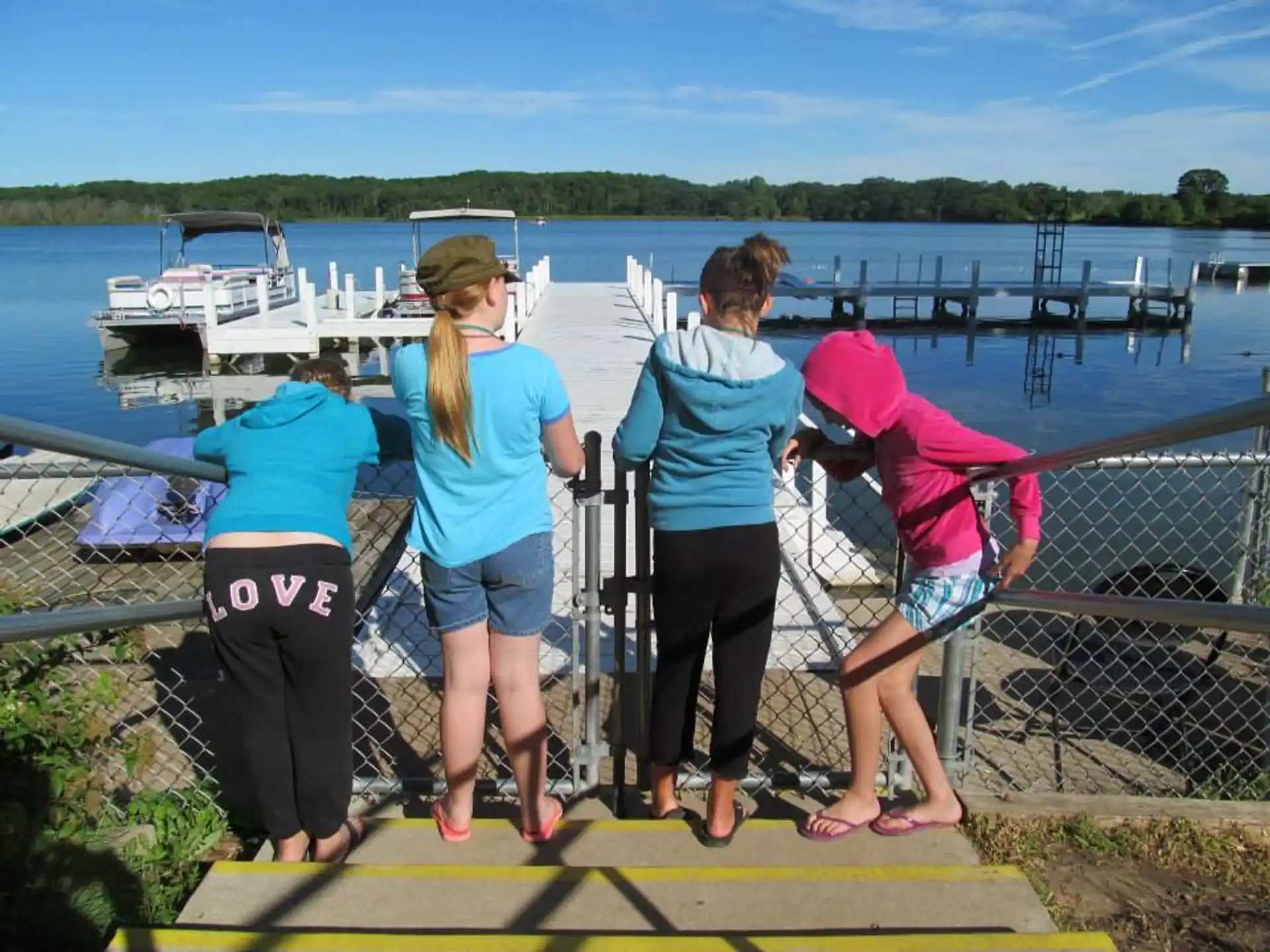 a group of women standing on a dock by a body of water