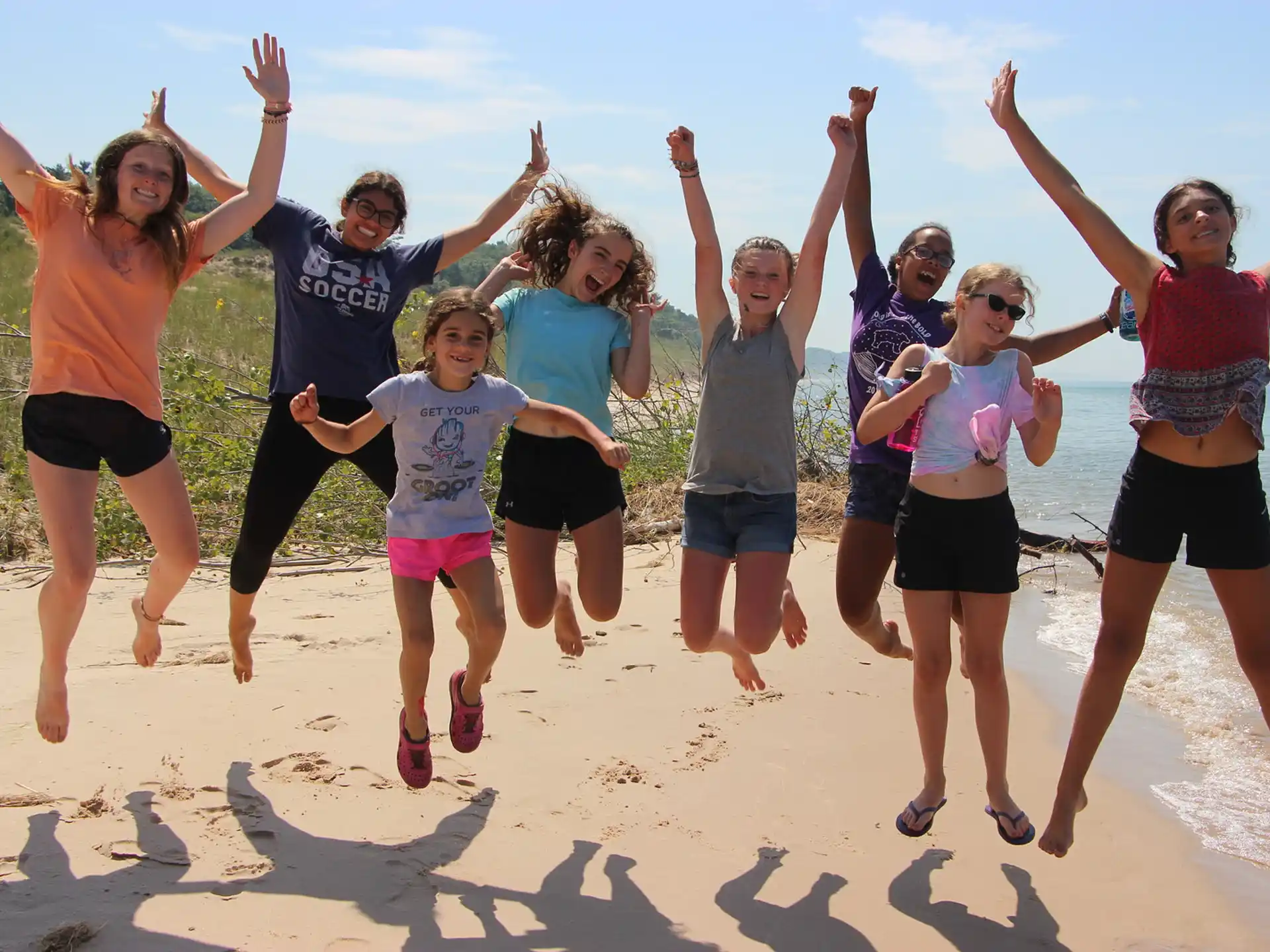 a group of people jumping in the air on a beach