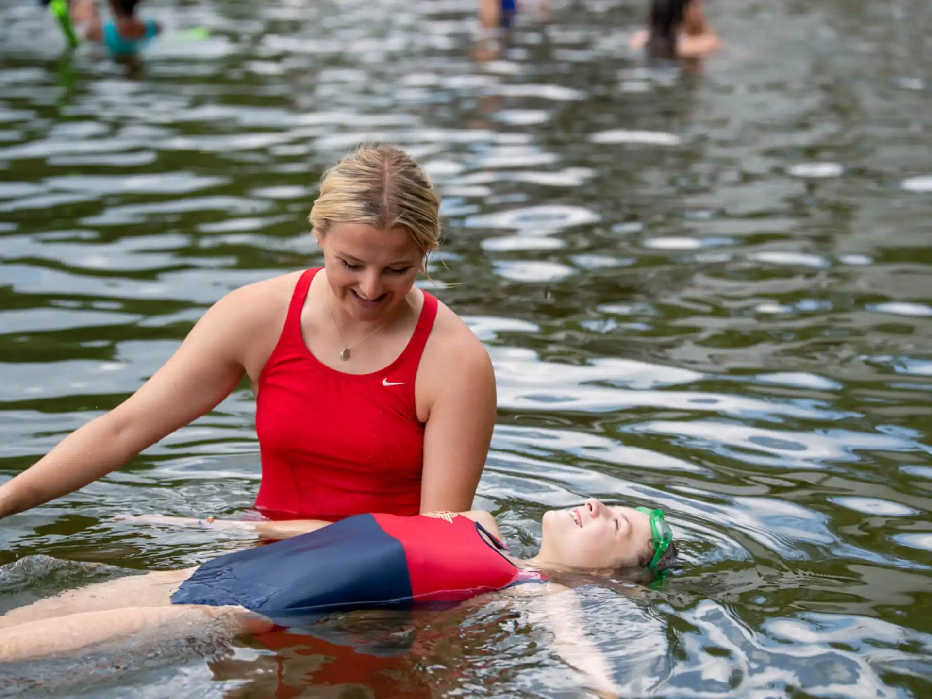 a person in a red garment in water with a baby in the lap