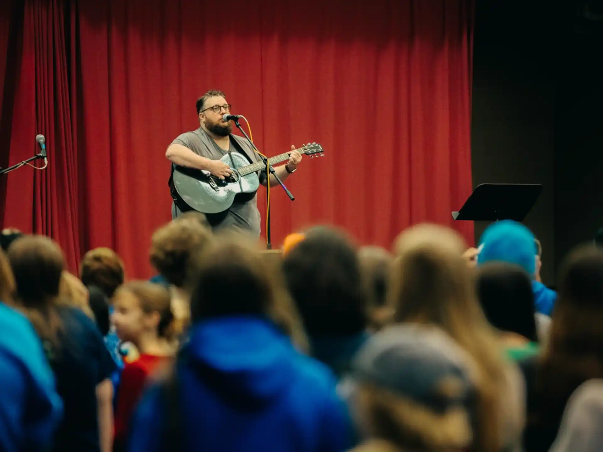 a person playing a guitar on a stage with a crowd watching