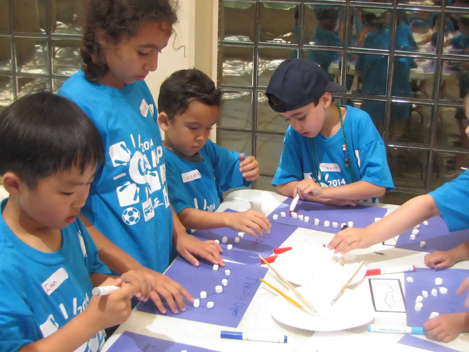 a group of boys sitting at a table with colored pencils