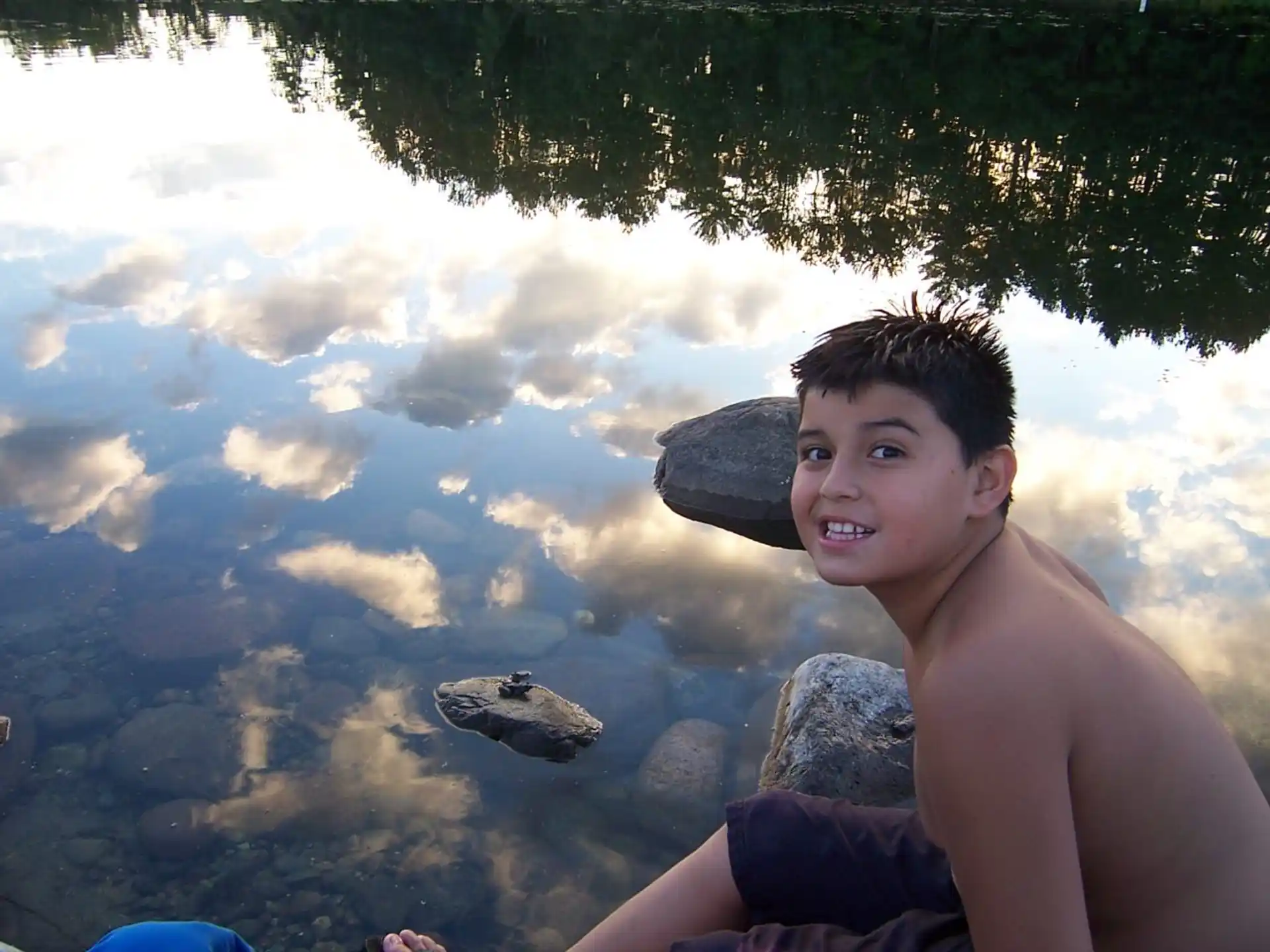 a person sitting on a rock by a body of water