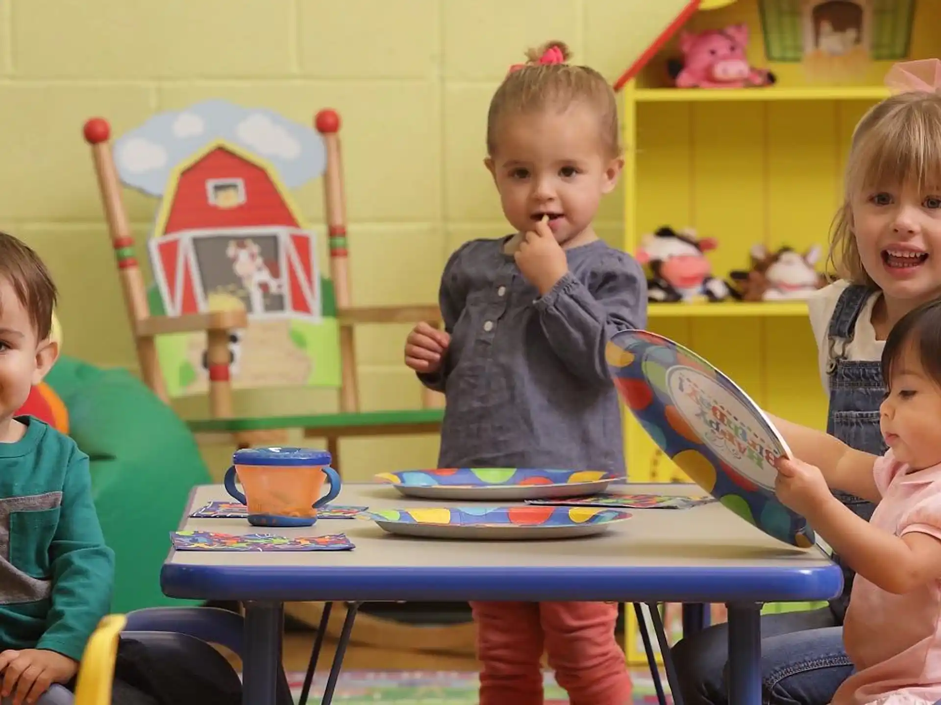 a group of children sitting at a table with toys