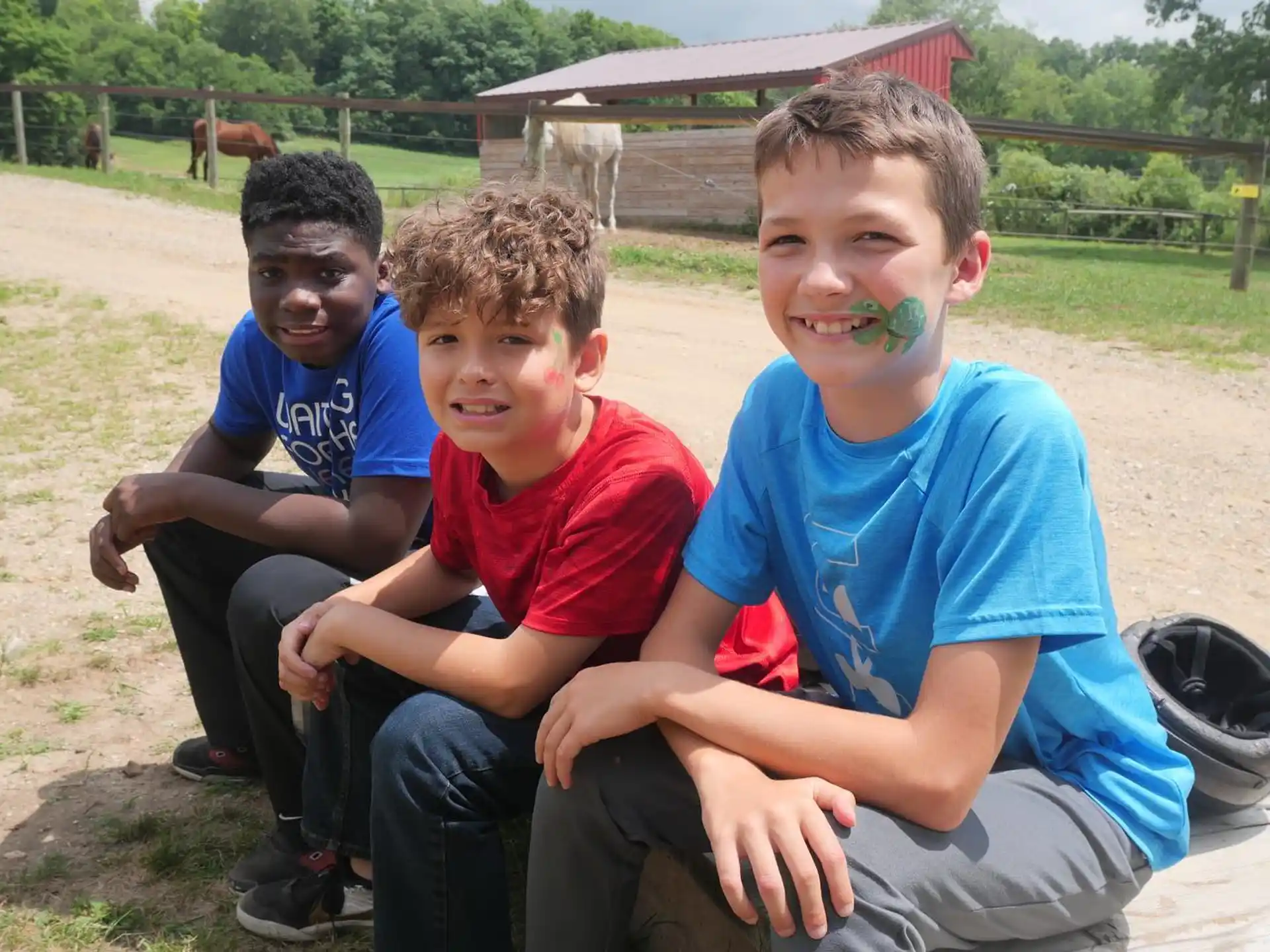 a group of boys sitting on the ground with paint on their faces
