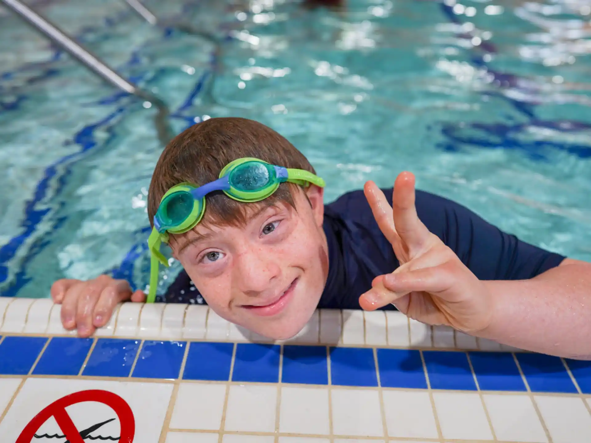 a person in a pool wearing goggles and a green hat