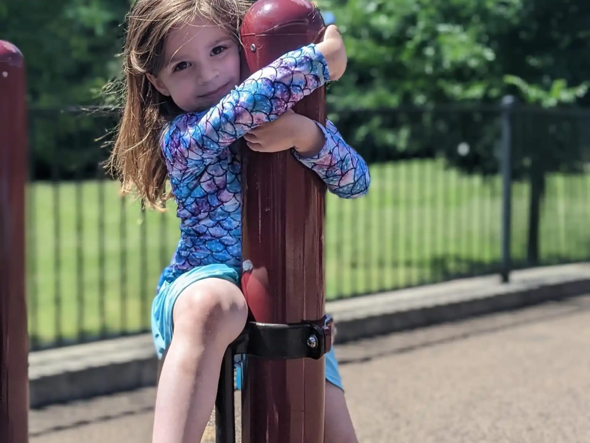 a girl sitting on a pole