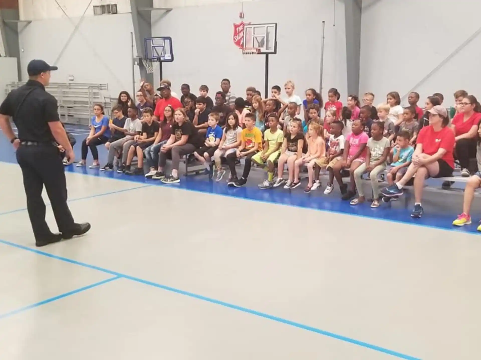 a person standing in front of a group of people sitting on a blue mat