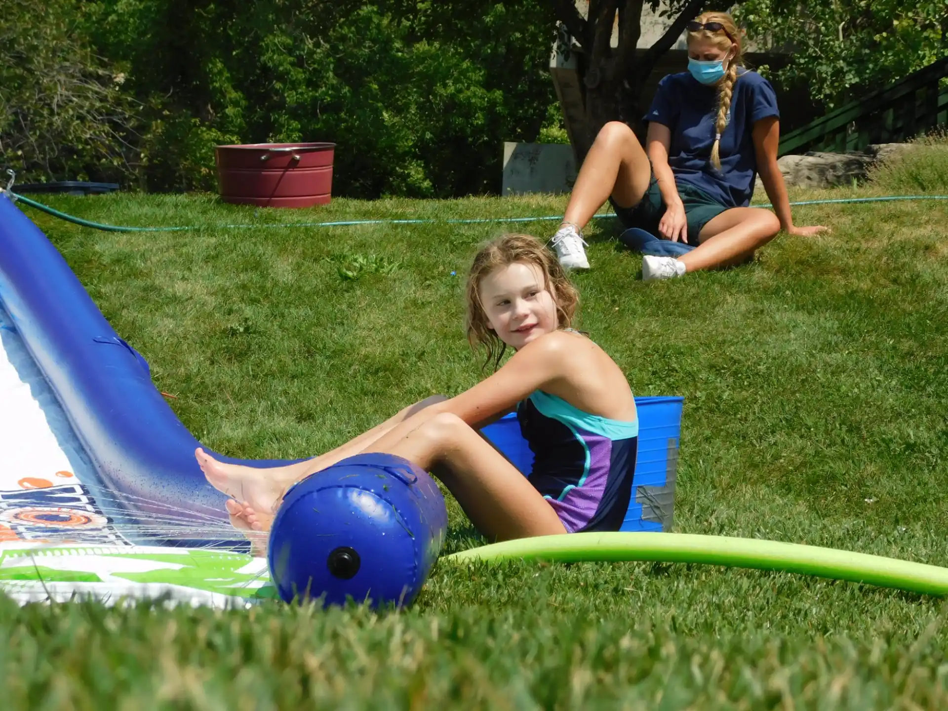 a girl lying on a mat in a grassy area with a blue ball