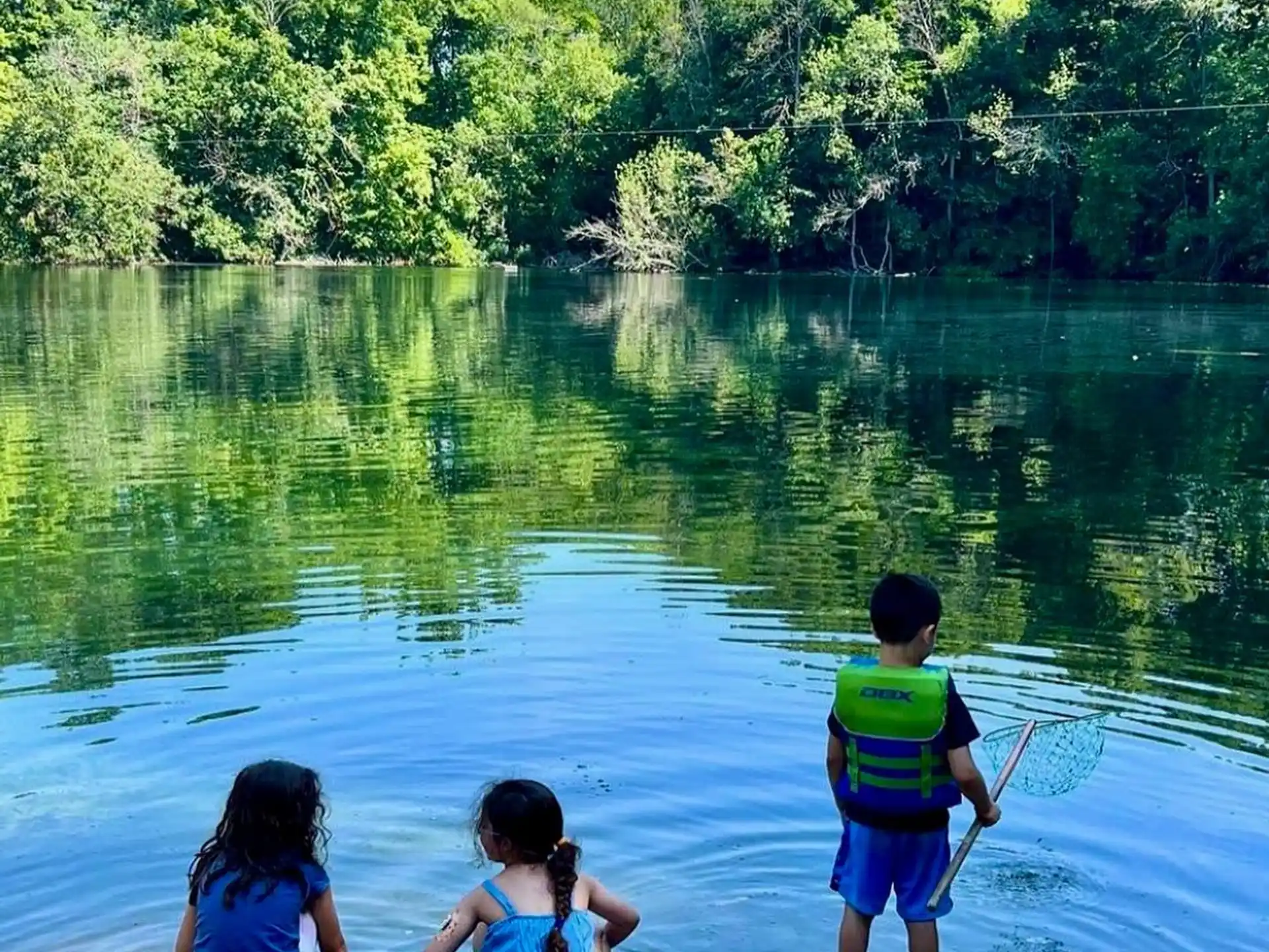 a group of children sitting on a rock by a lake