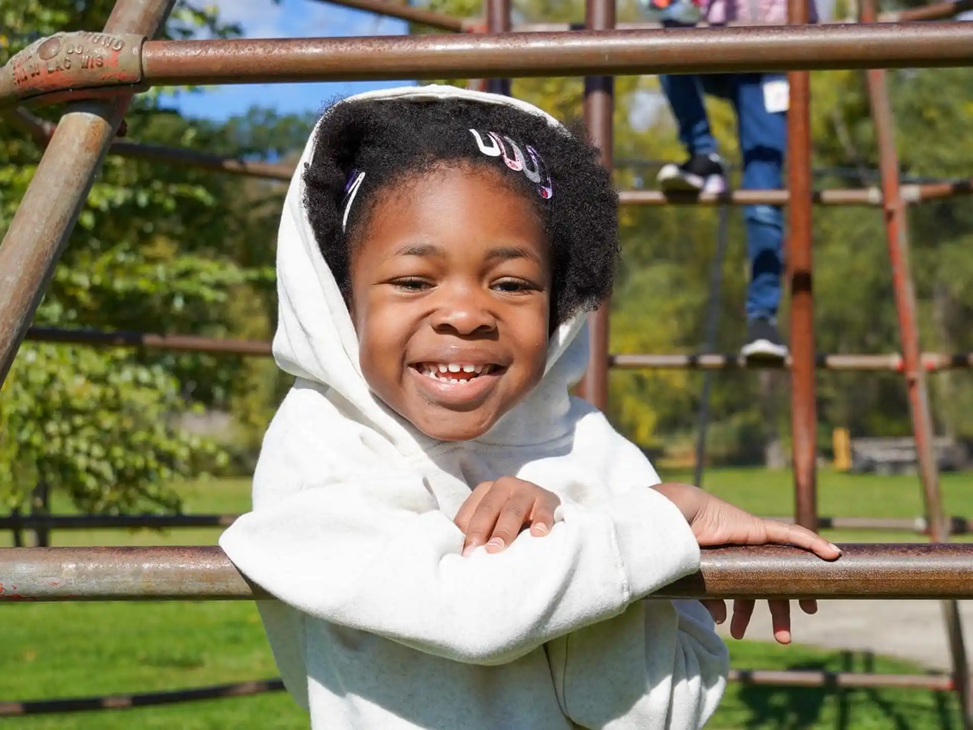 a child smiling with a fence in the background