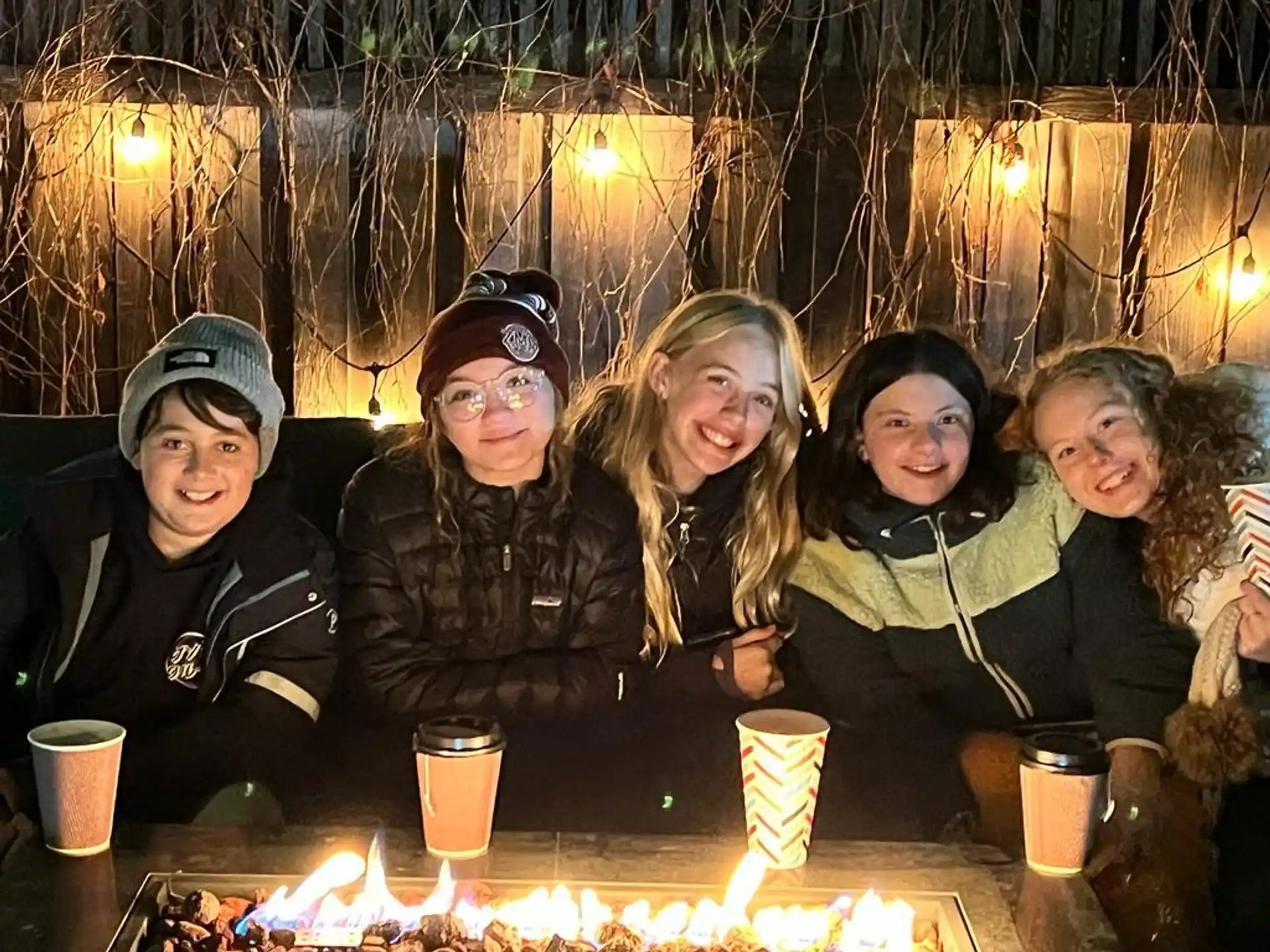 a group of people sitting at a table with a fire in front of them