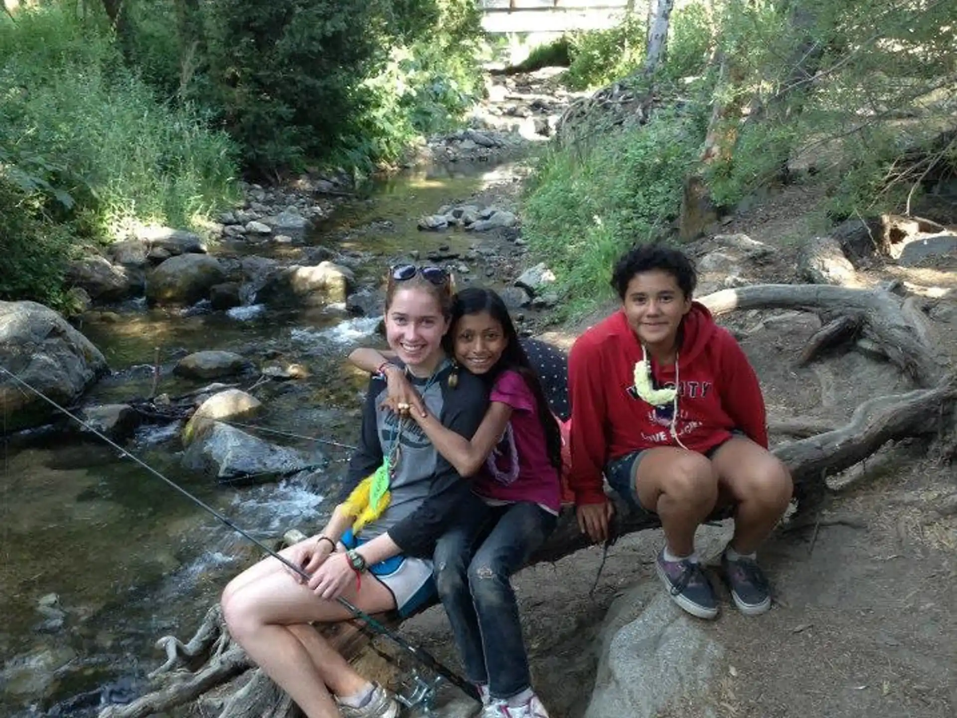 a group of people sitting on a log in a stream