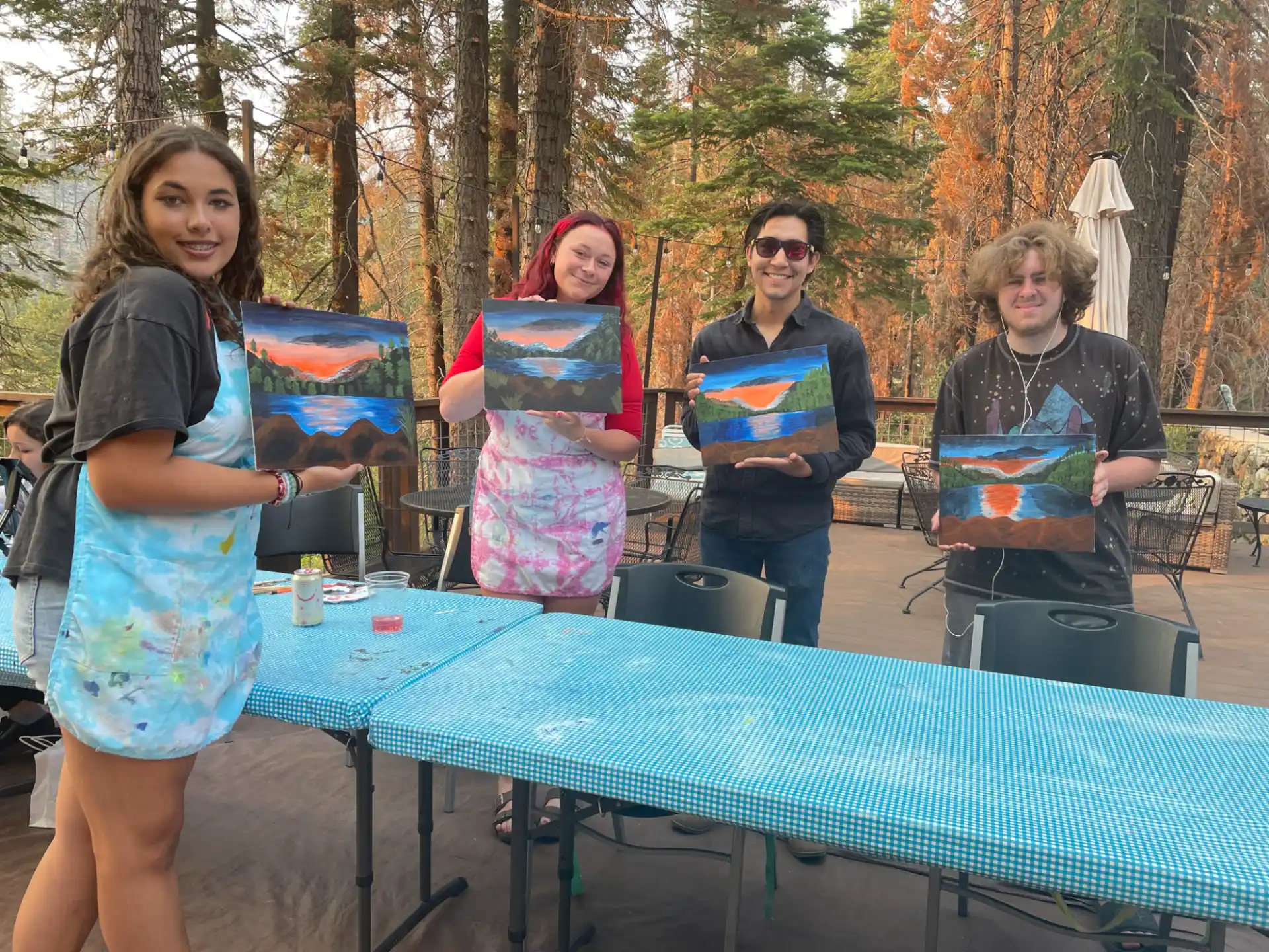 a group of people standing around a table with a blue tablecloth