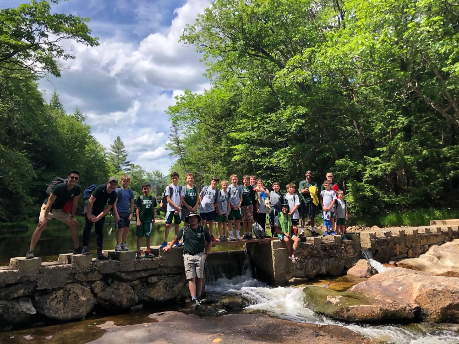 a group of people standing on rocks by a river
